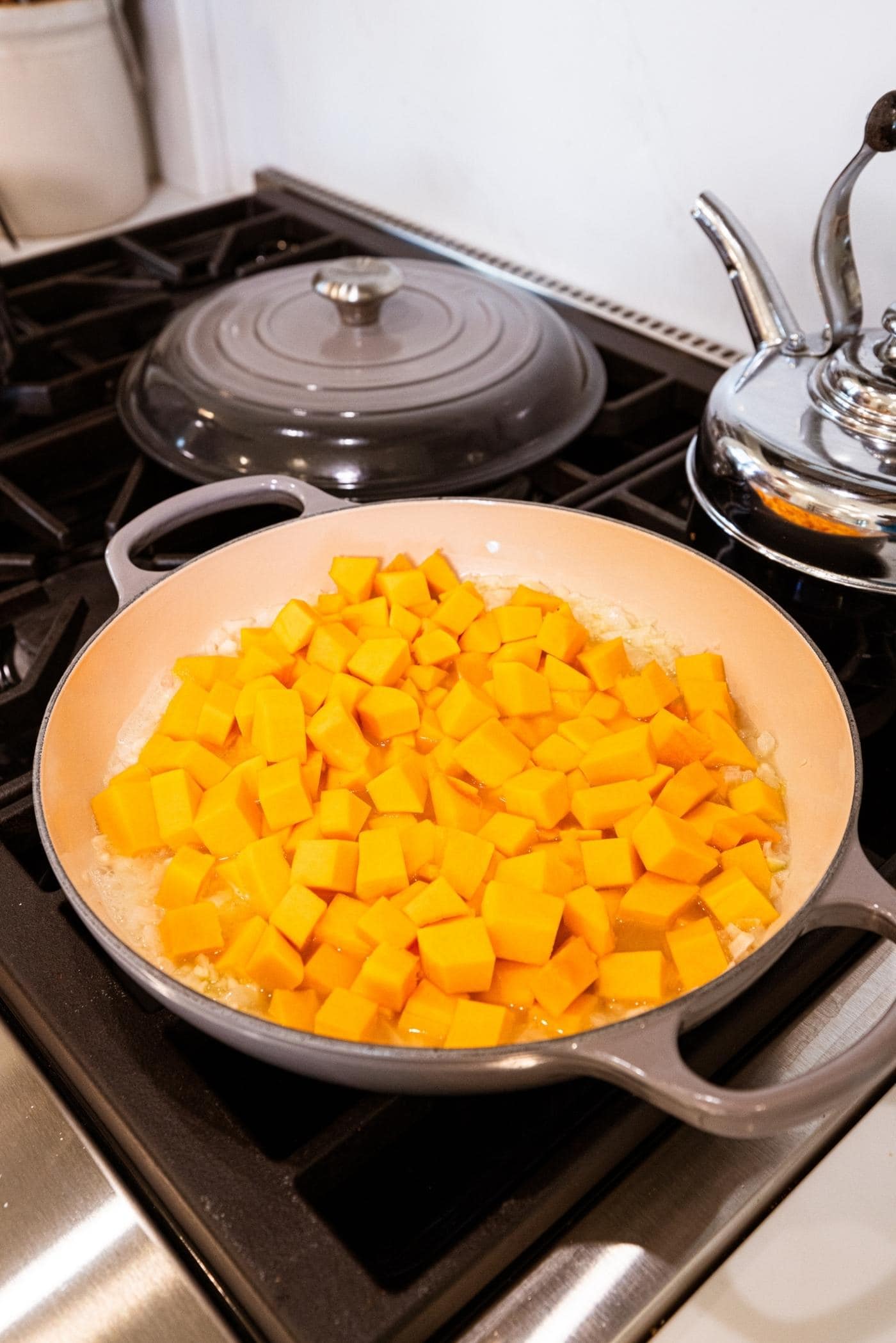 Large pot on the stovetop with pieces of cubed butternut squash before cooking in liquid.