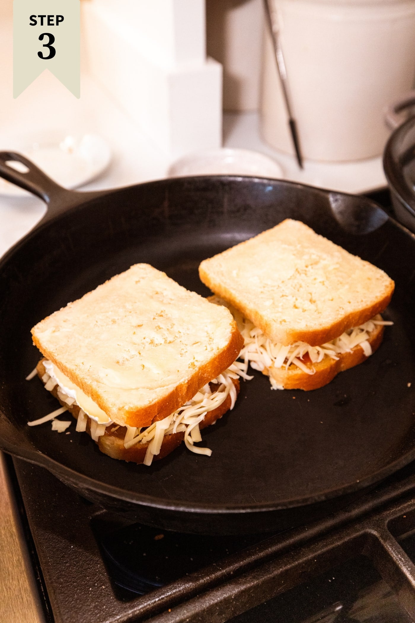 Large black skillet with two grilled cheese sandwiches with cheese falling out.