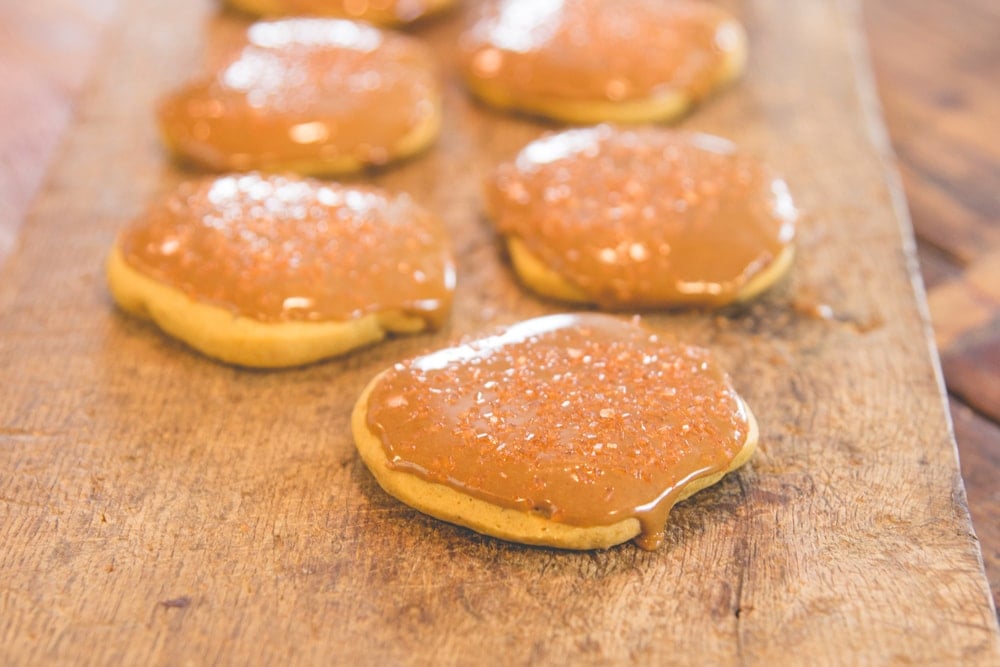 A row of pumpkin cookies sits on a wooden block.