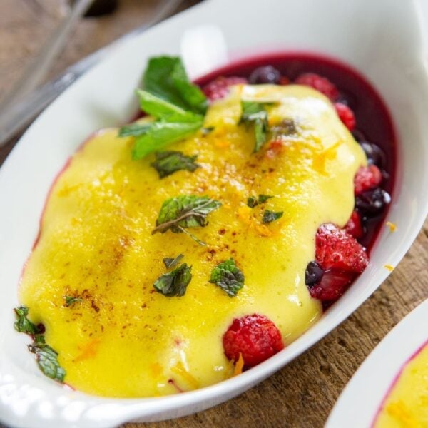 Berries topped with sabayon in a dish.