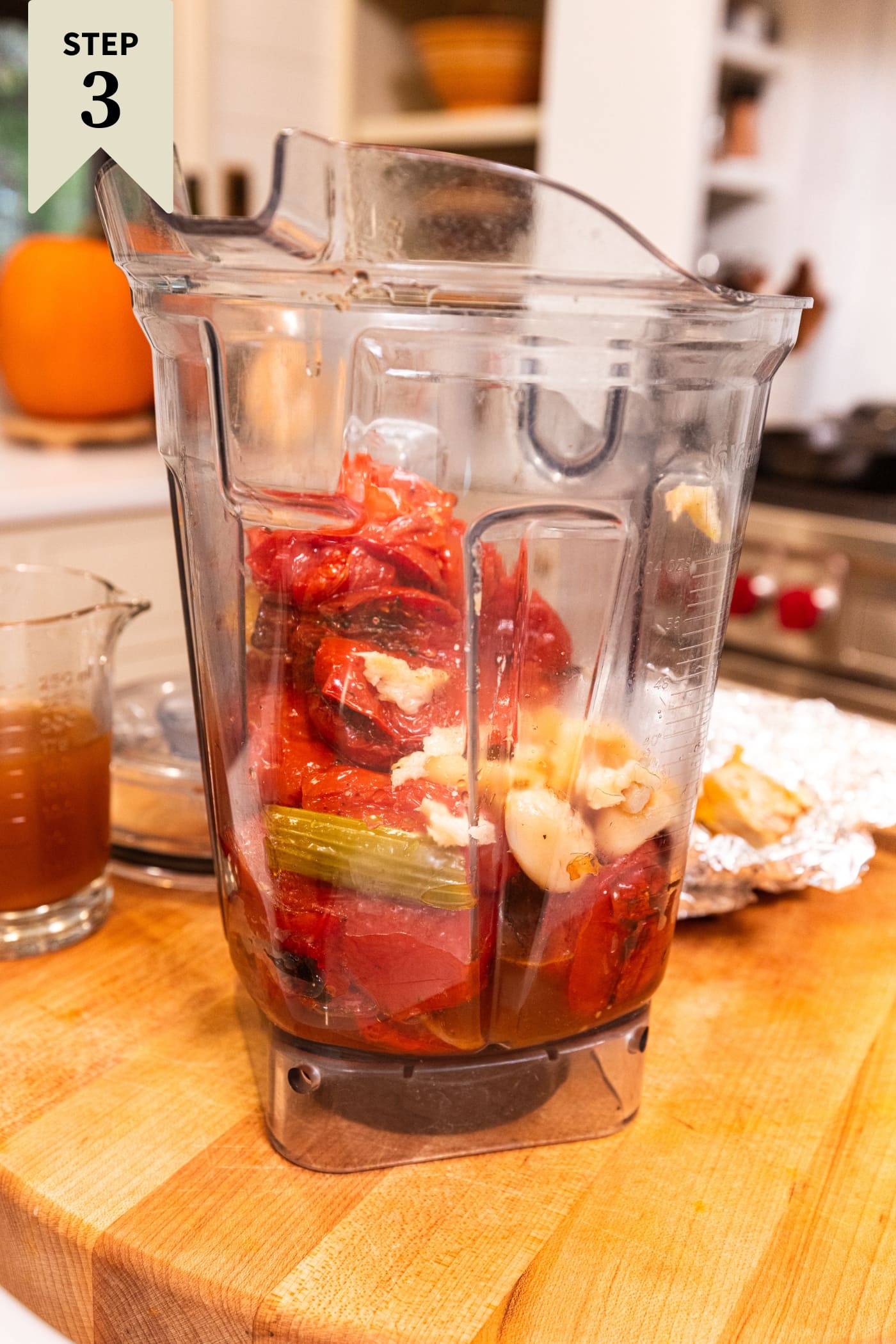 Large canister of blender filled with roasted tomatoes and other vegetables before being blended together.