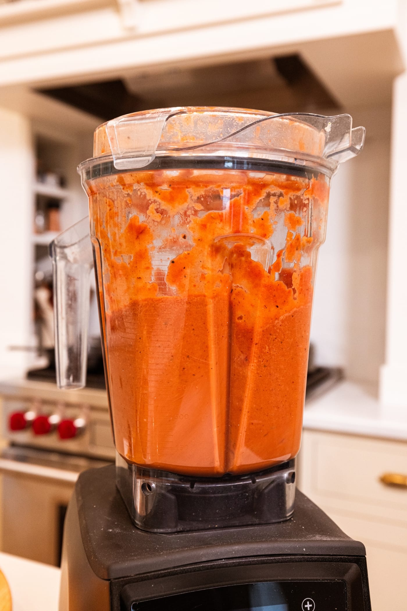 Blender canister sitting on its base after blending roasted tomatoes with other vegetables into a roasted tomato soup.