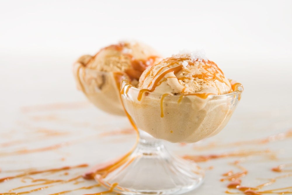 Two scoops of ice cream sit in a glass dish.