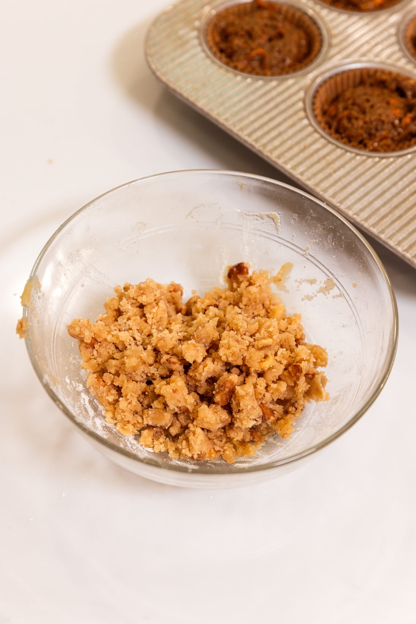 Glass bowl filled with streusel topping after being mixed together with nuts showing.