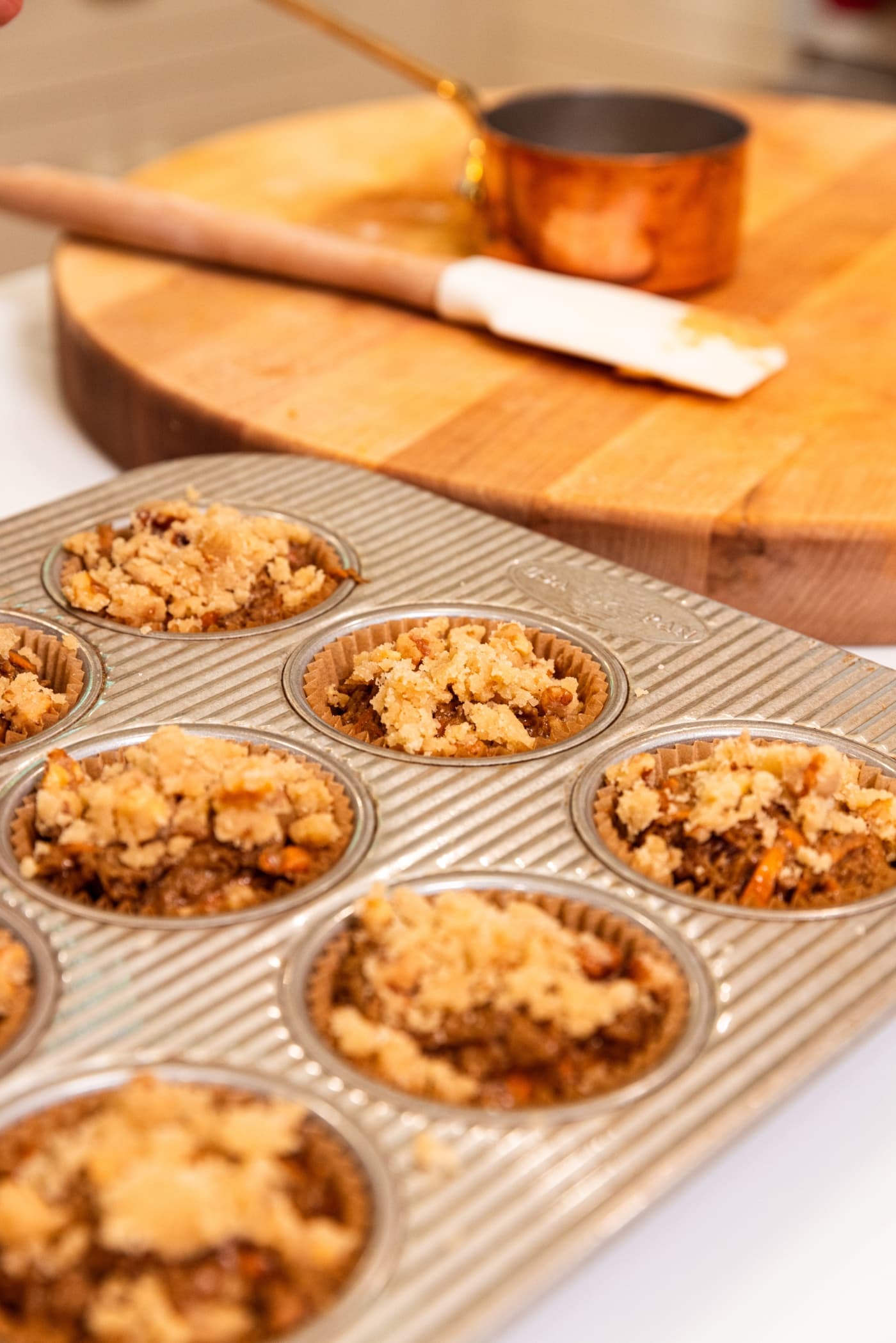 Streusel resting on top of unbaked muffins in muffin tin.