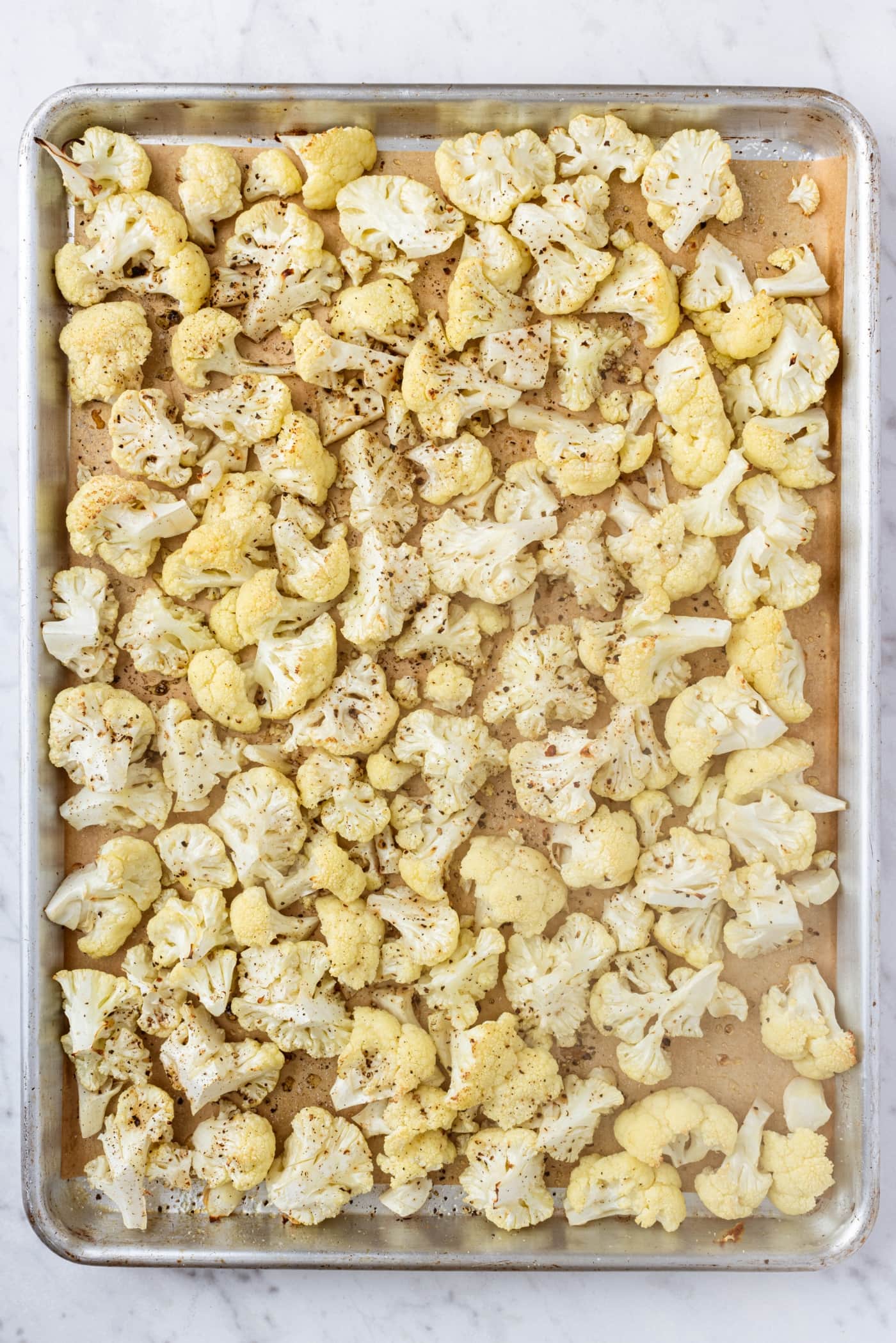 Freshly roasted cauliflower florets on metal baking dish right after coming out of the oven.