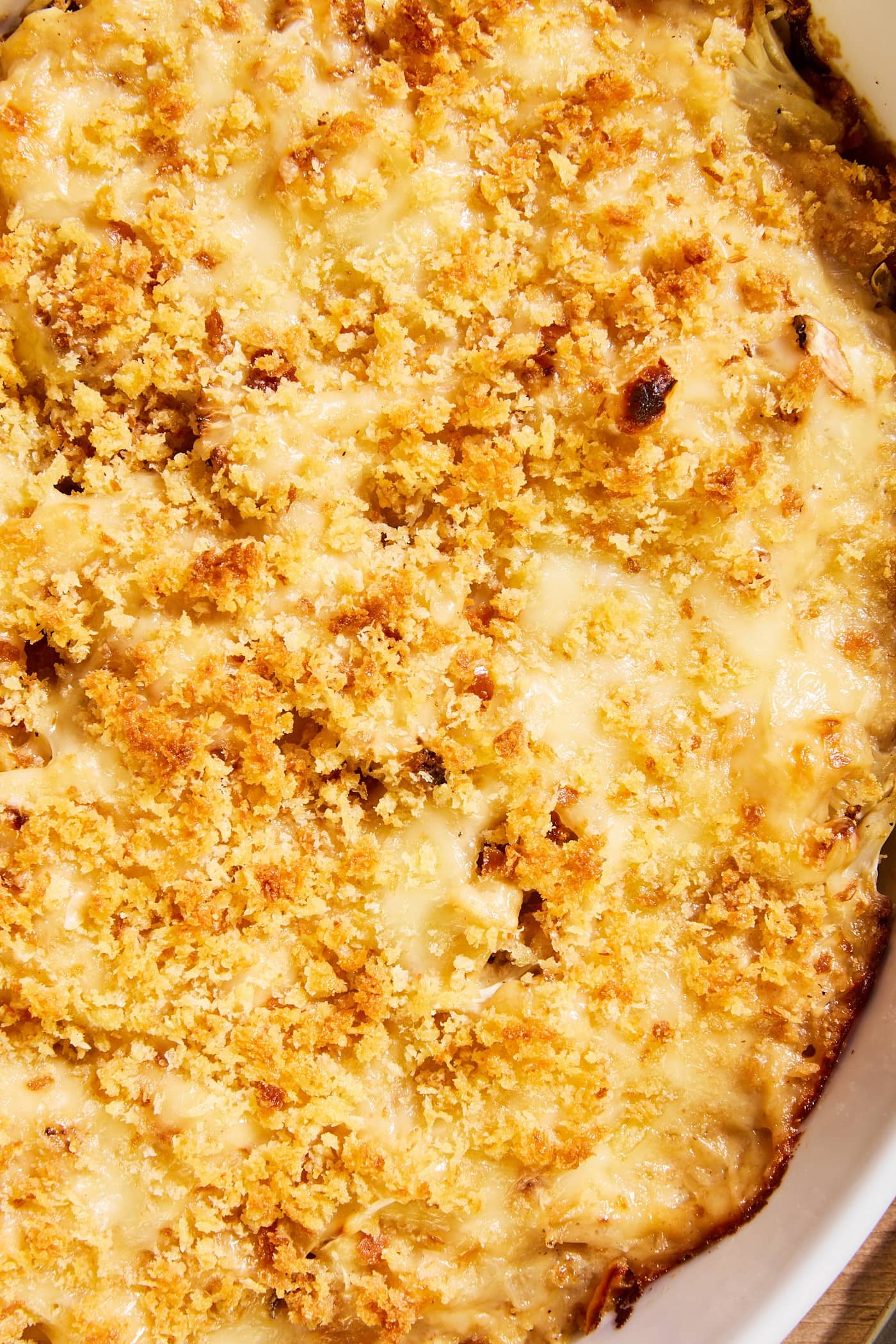 White baking dish filled with cauliflower au gratin with crispy browned topping along with cheese.