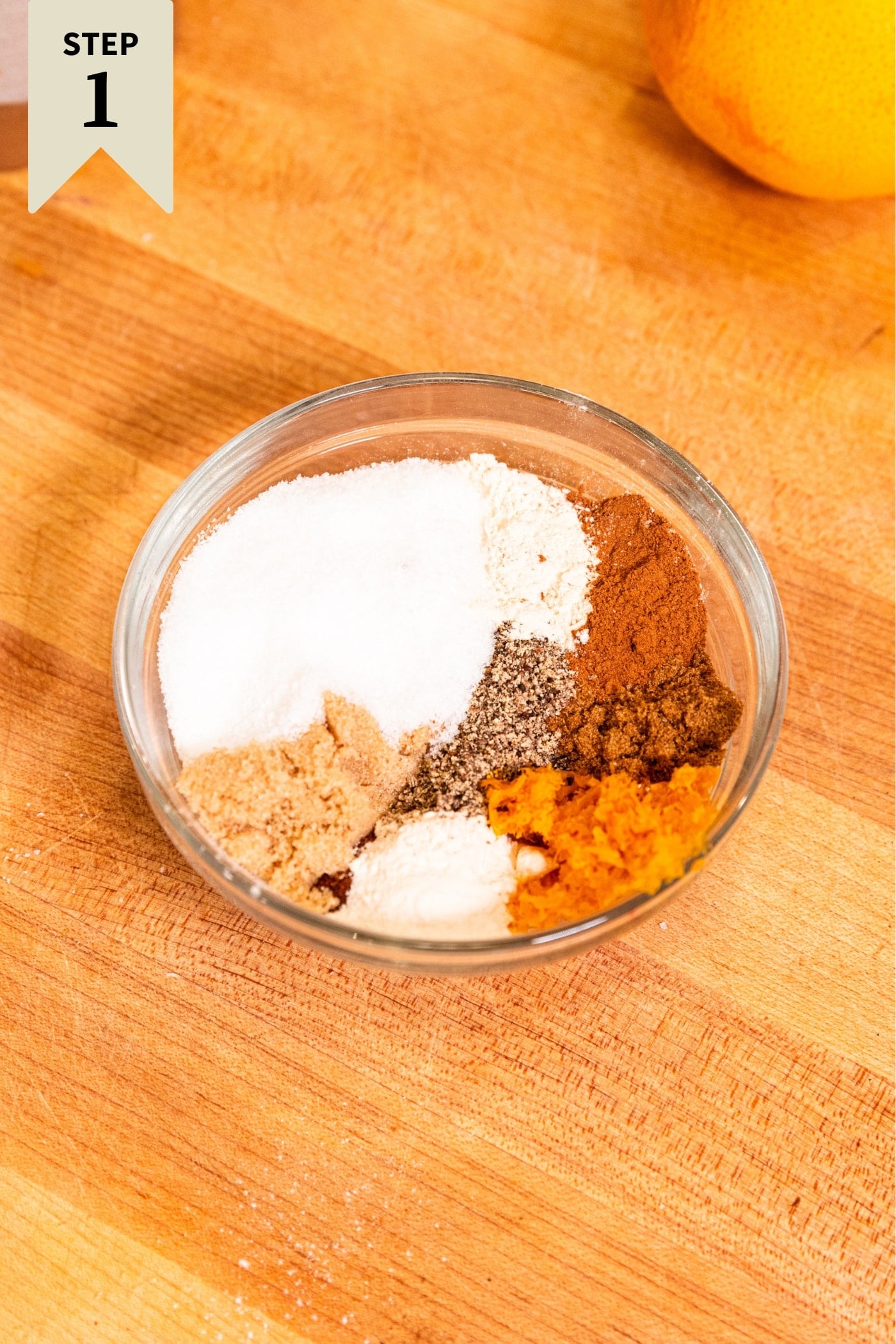 Glass bowl filled with lots of spices to be mixed together for a Thanksgiving turkey on wooden cutting board.