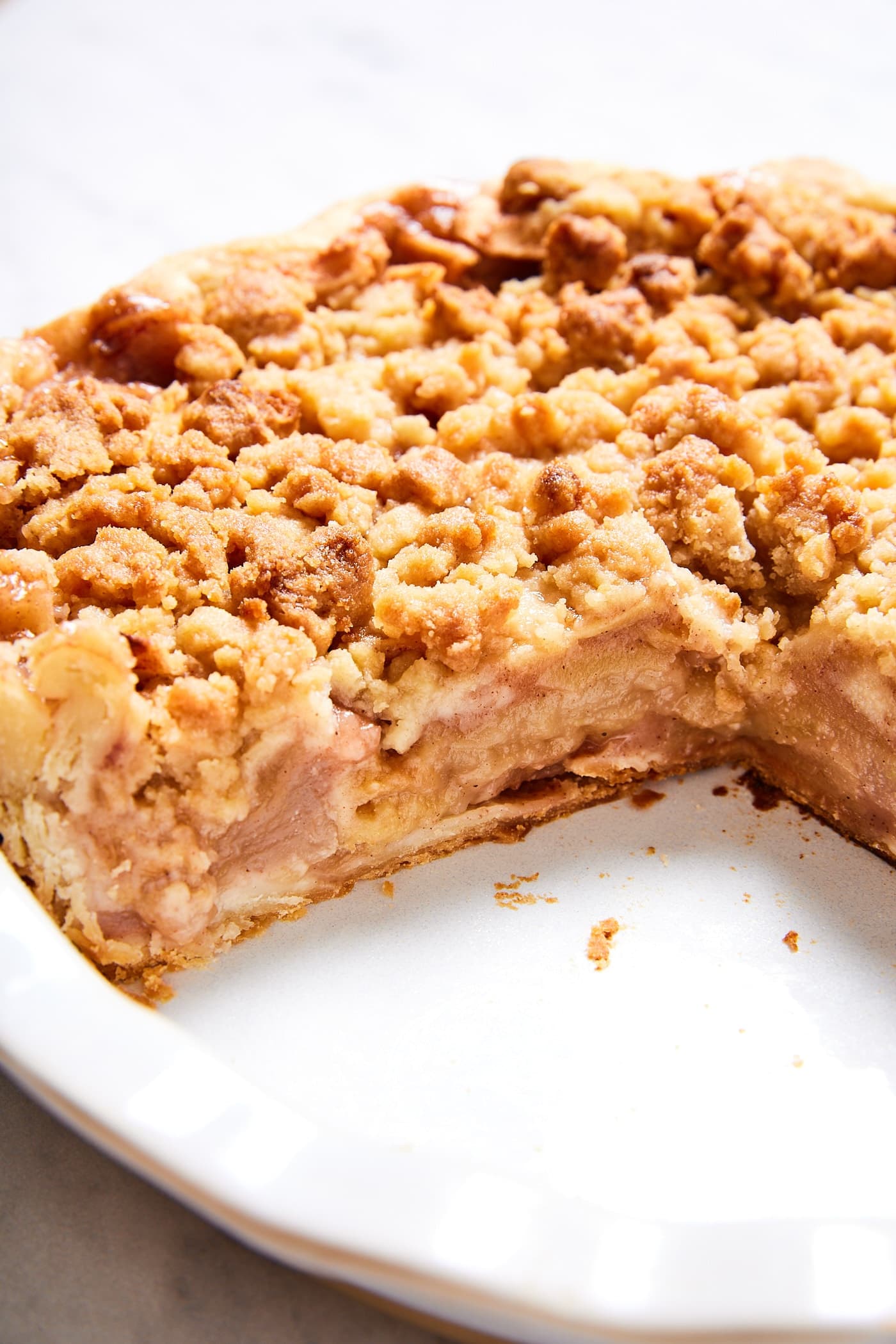 Classic apple pie with slices removed showing the side of the pie with all of the layers of apples and streusel topping.