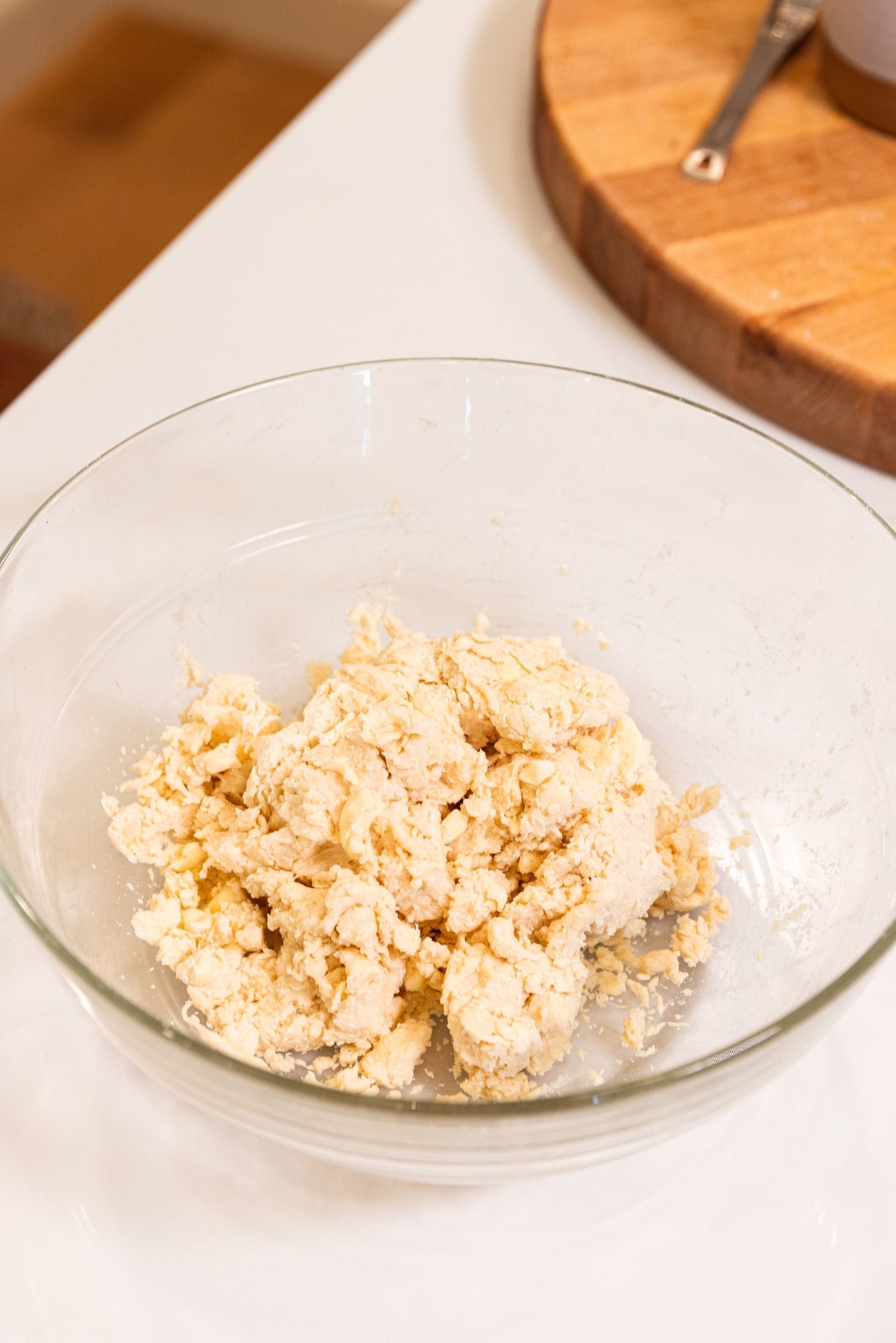 Glass bowl filled with pie dough that has not been pressed together yet showing shaggy texture.