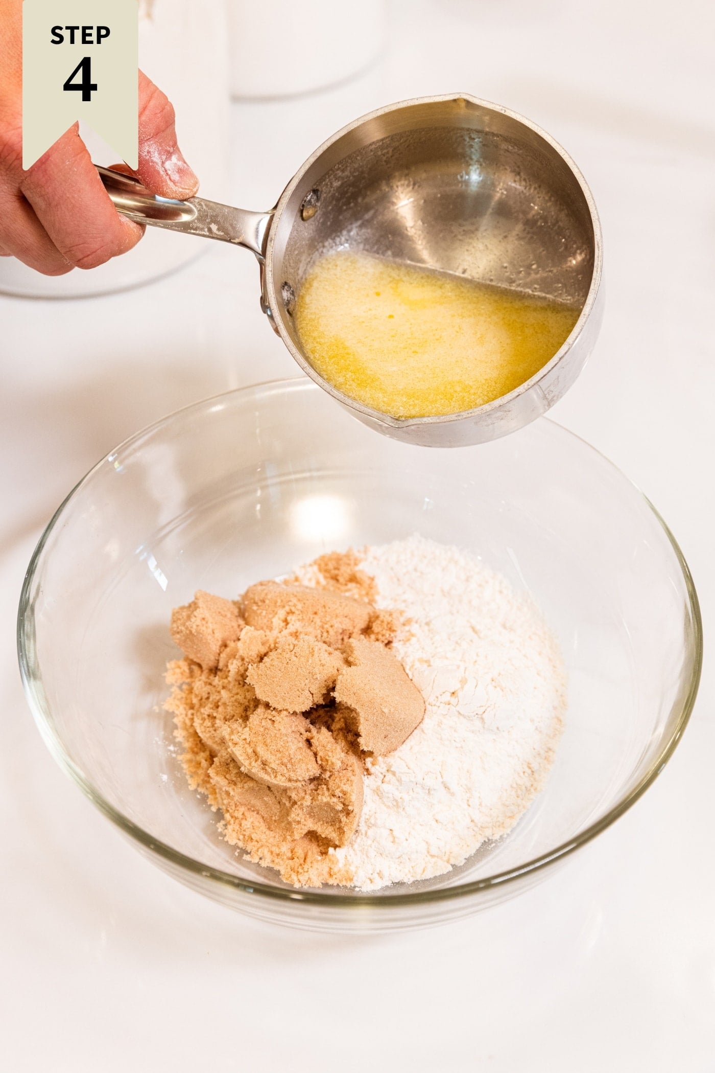 Small saucepan filled with melted butter being poured into a bowl with brown sugar and white granulated sugar.
