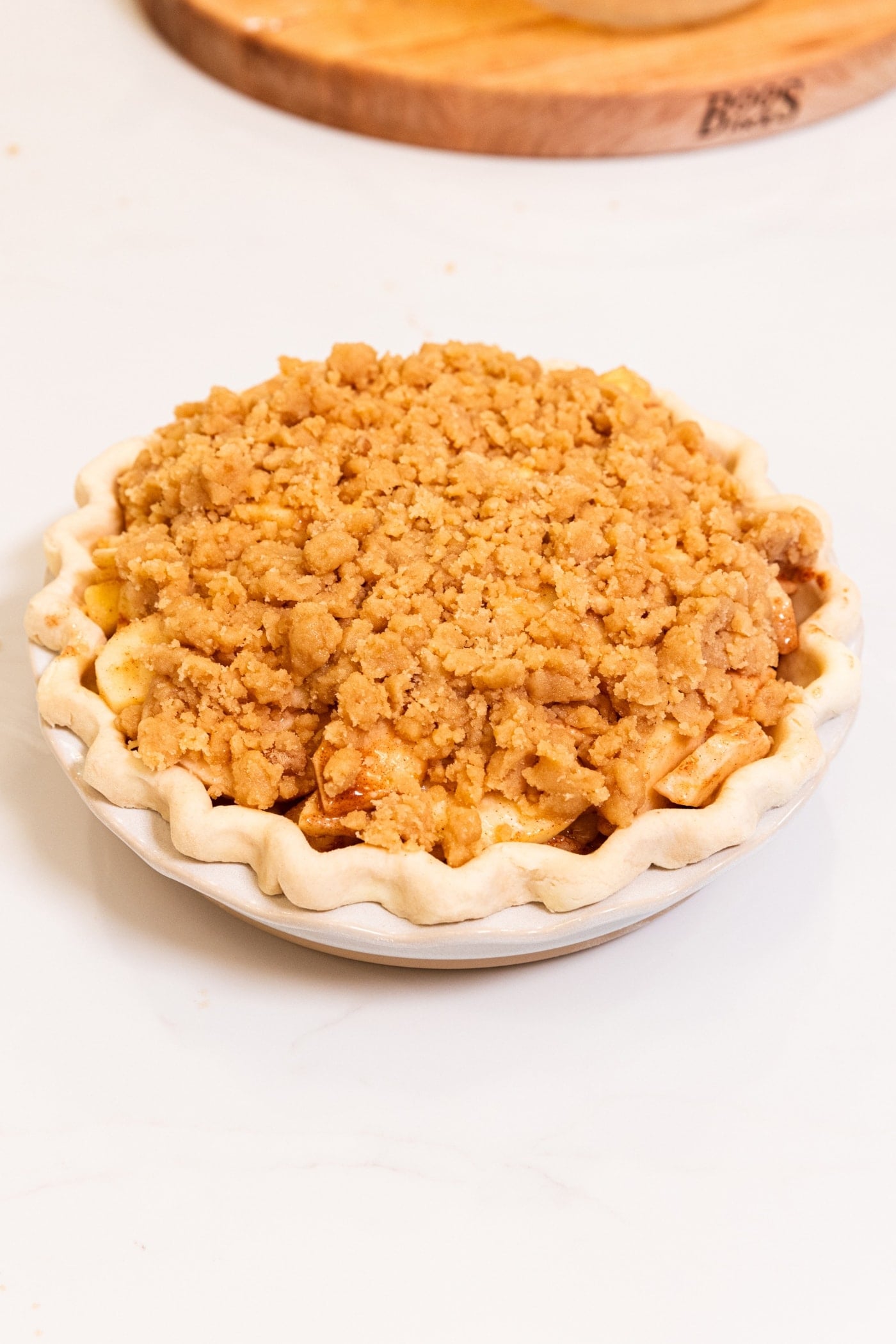 A round pie crust with a streusel topping all over right before going into the oven.