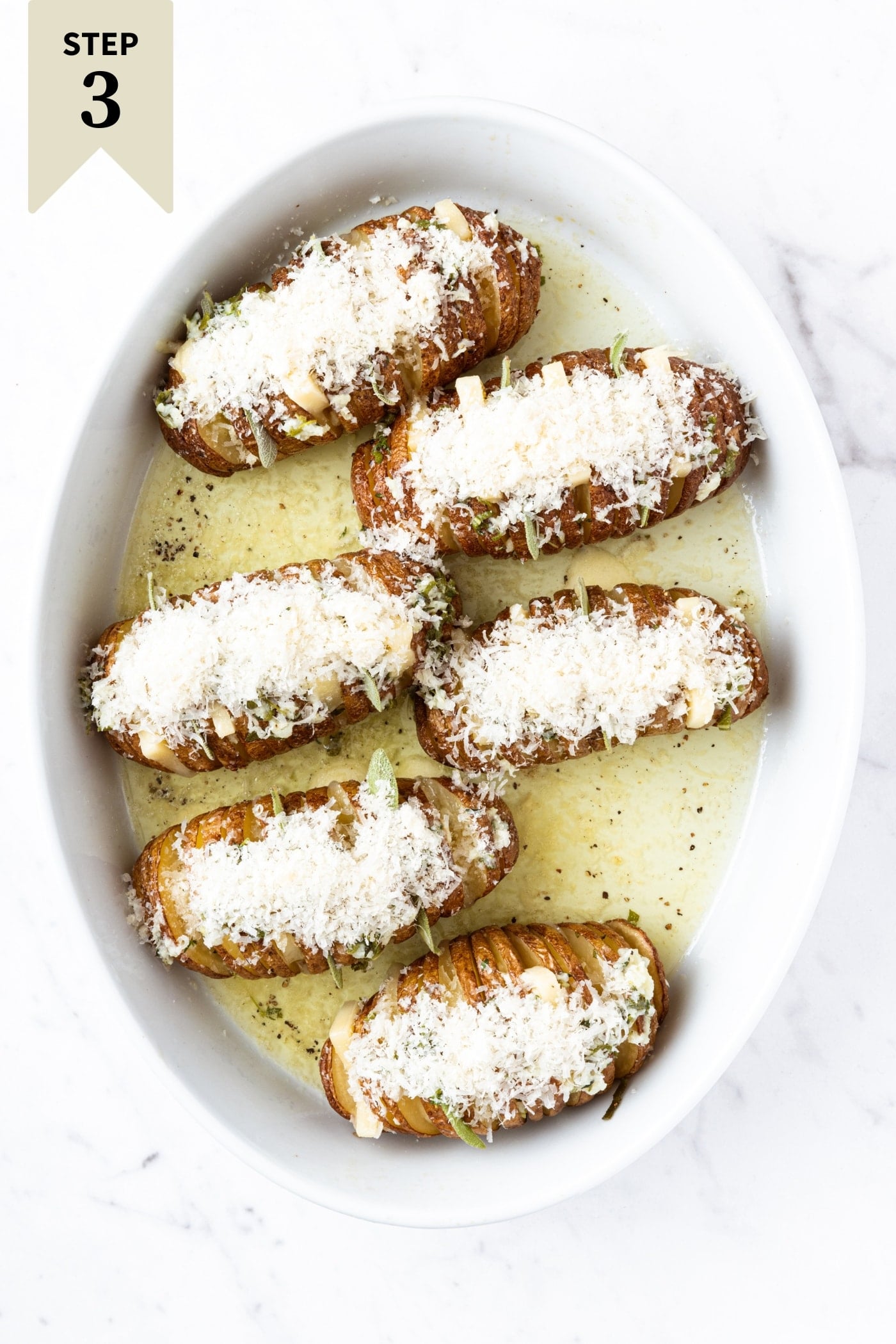 Hasselback potatoes covered with cheese mixture and drizzled with garlic butter before being roasted.