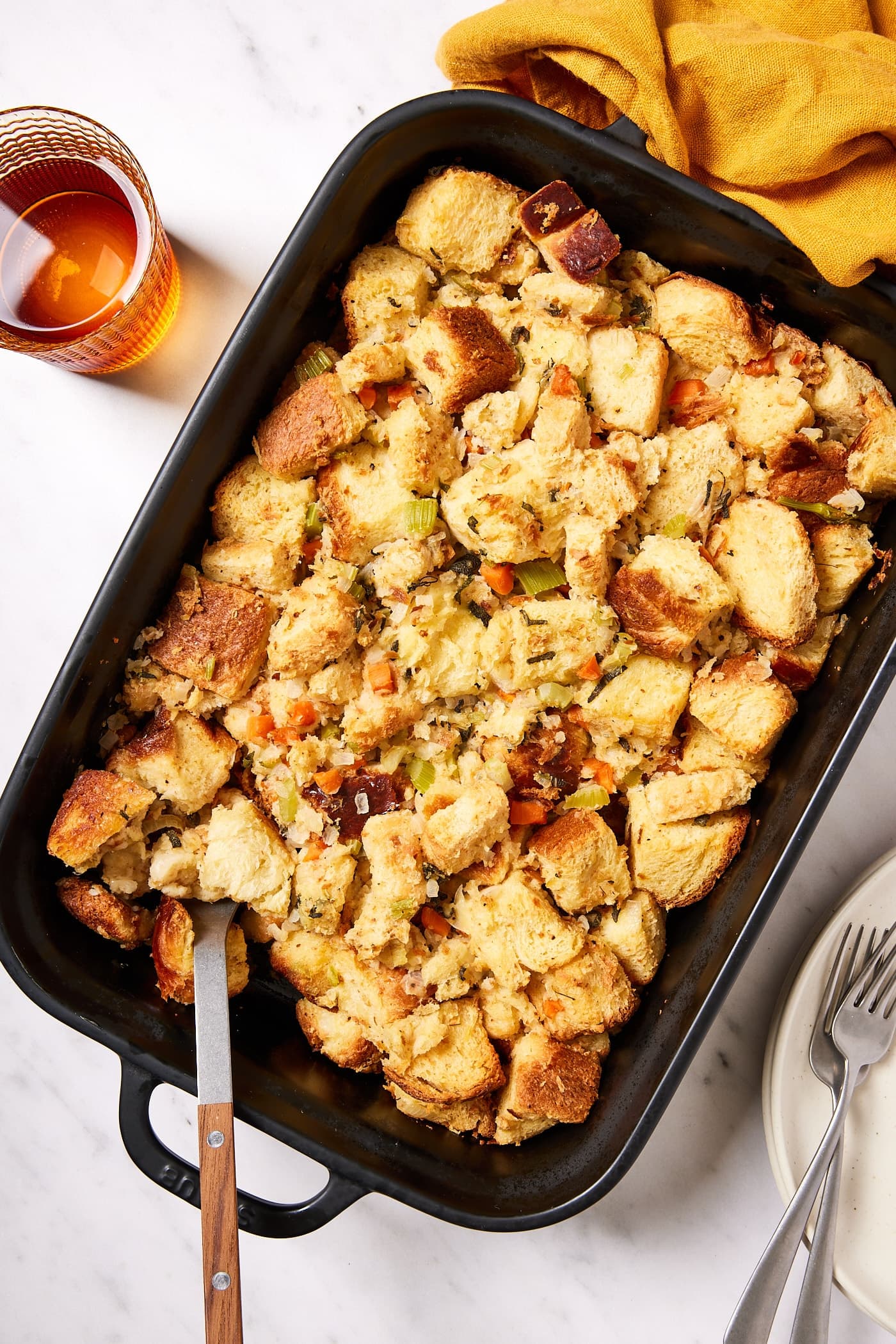 Large rectangular baking dish filled with baked traditional stuffing with sprinkling of cooked vegetables on top.
