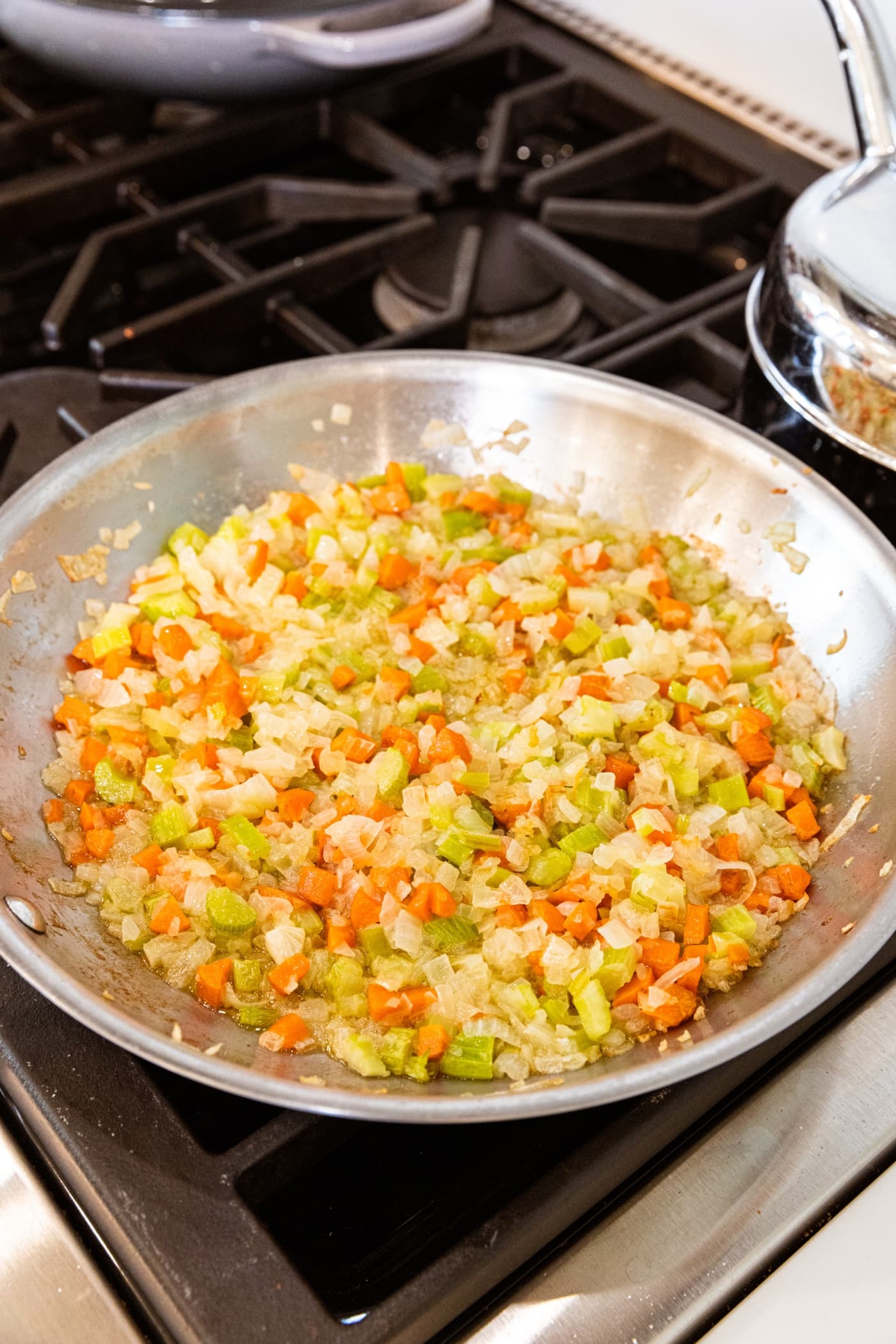 Cooked chopped vegetables sitting in metal skillet after cooking in butter on the stovetop.