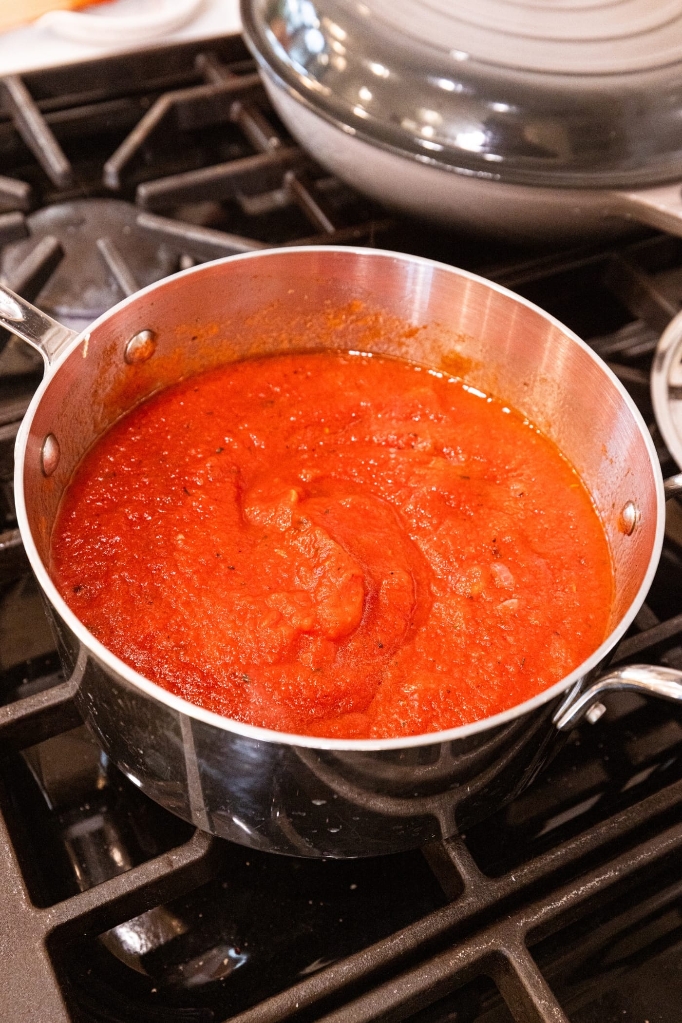 Pot on the stovetop filled with tomato sauce after cooking and simmering.
