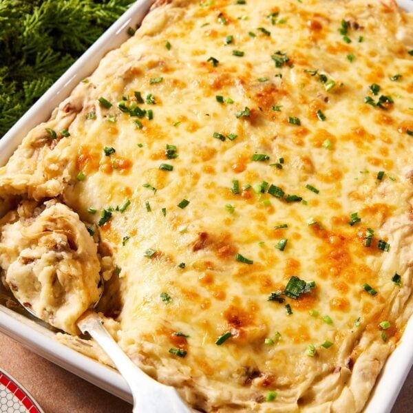 Large white baking dish filled with French onion potato casserole with cheese over the top and sprinkled with chopped parsley.