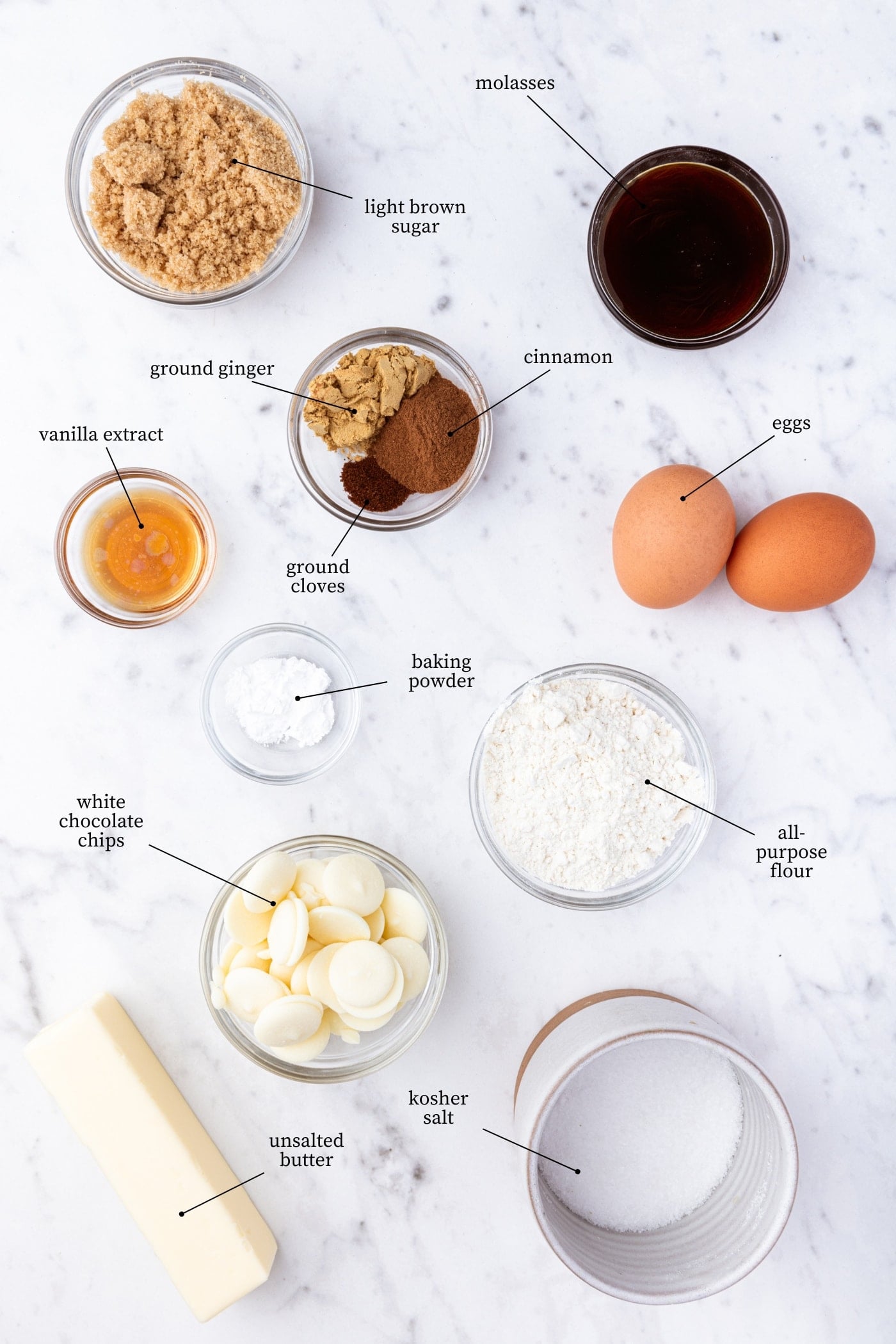 White marble surface filled with all ingredients needed for gingerbread blondies including eggs, spices, flour, butter, white chocolate, and more.