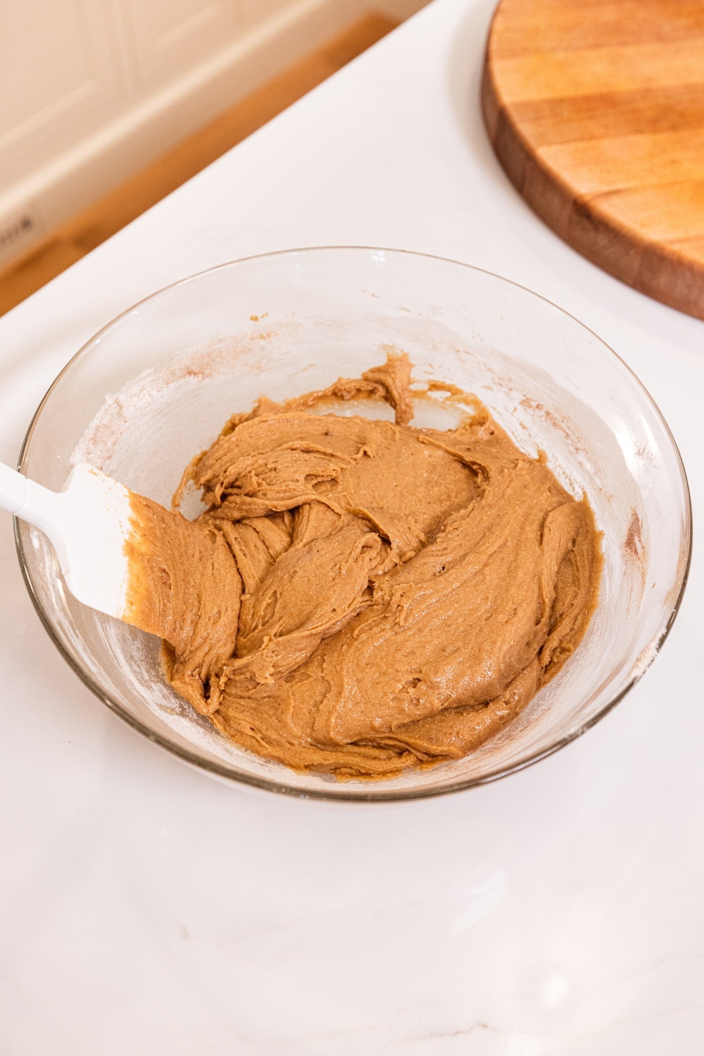 Glass bowl filled with batter for gingerbread blondies with spatula after mixing together.