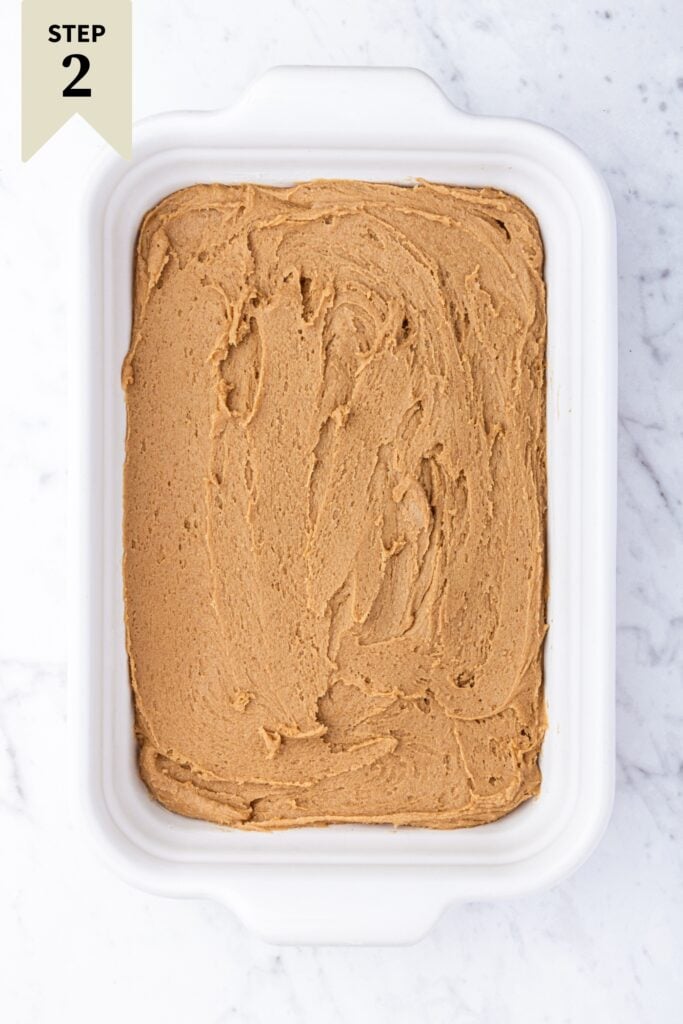 White rectangular baking dish with gingerbread blondie batter before being baked in oven on marble surface.