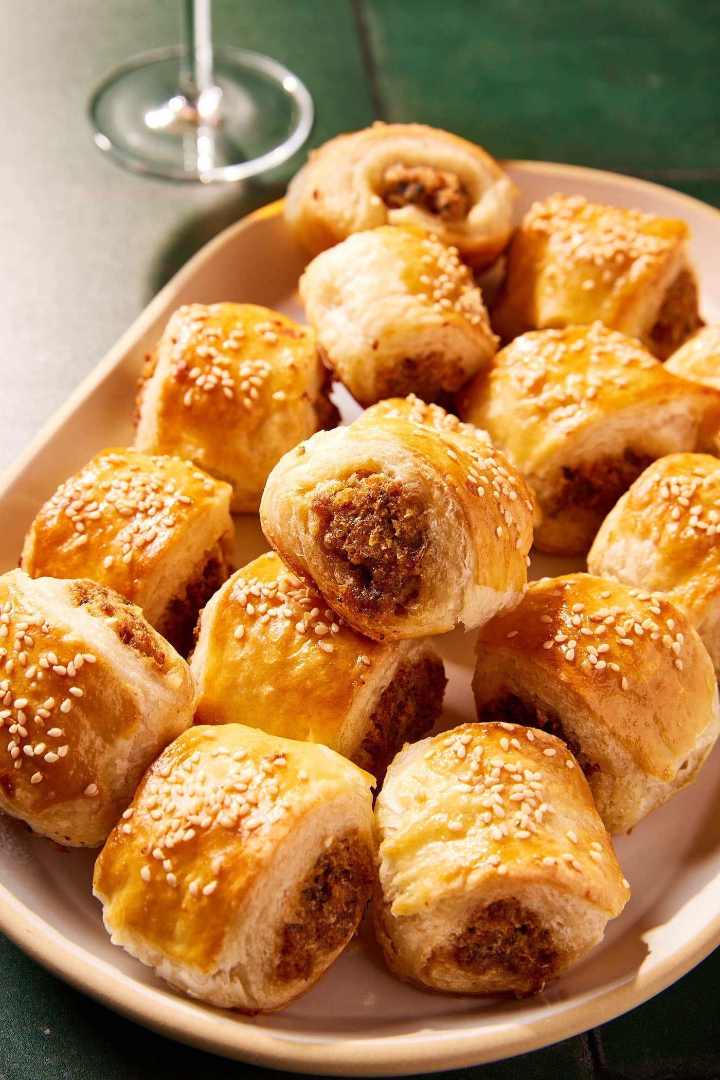Golden brown puff pastry bites sitting in a stack on a white platter with inside texture showing.
