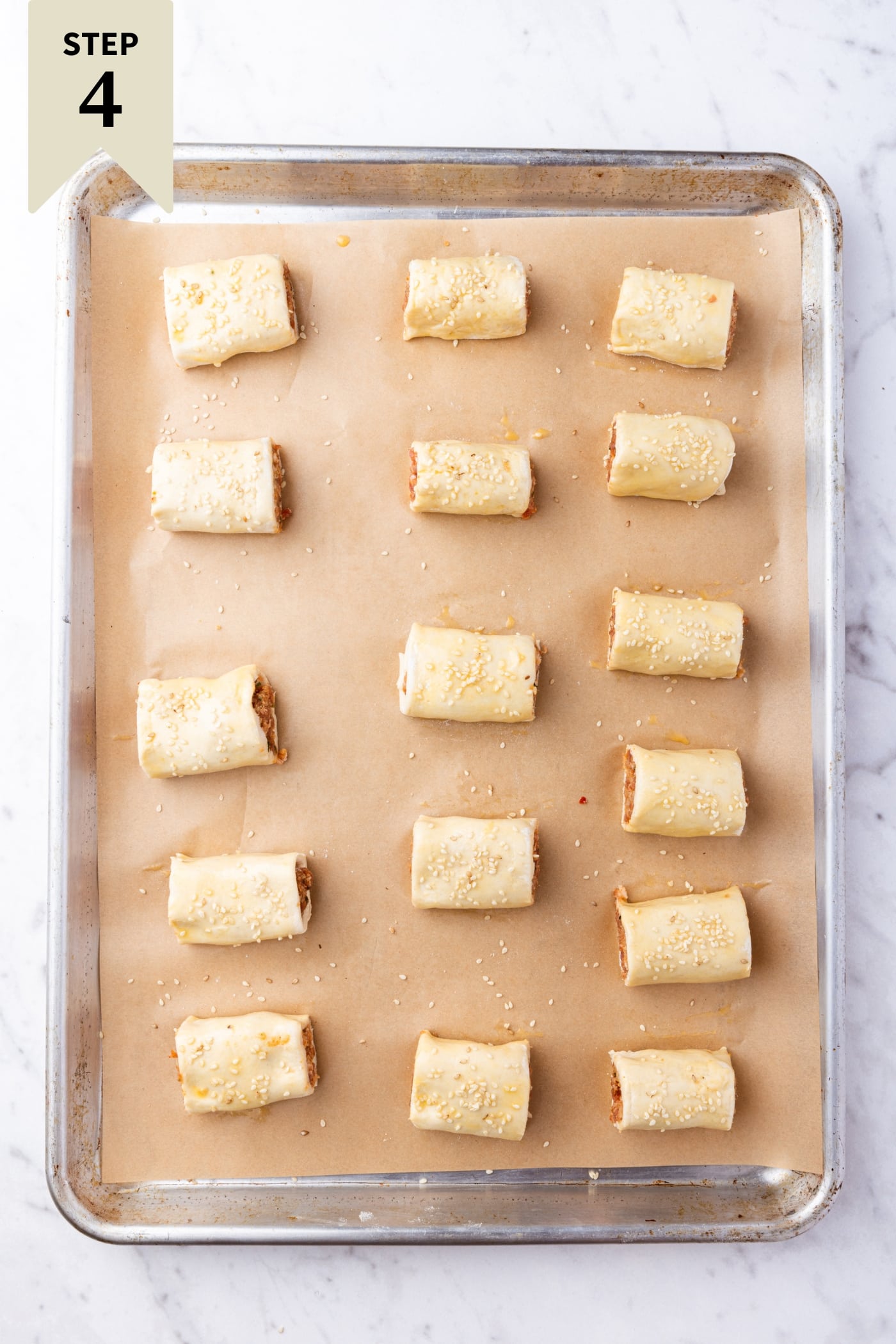 Metal baking sheet sitting on marble surface with unbaked bites right before going into the oven.