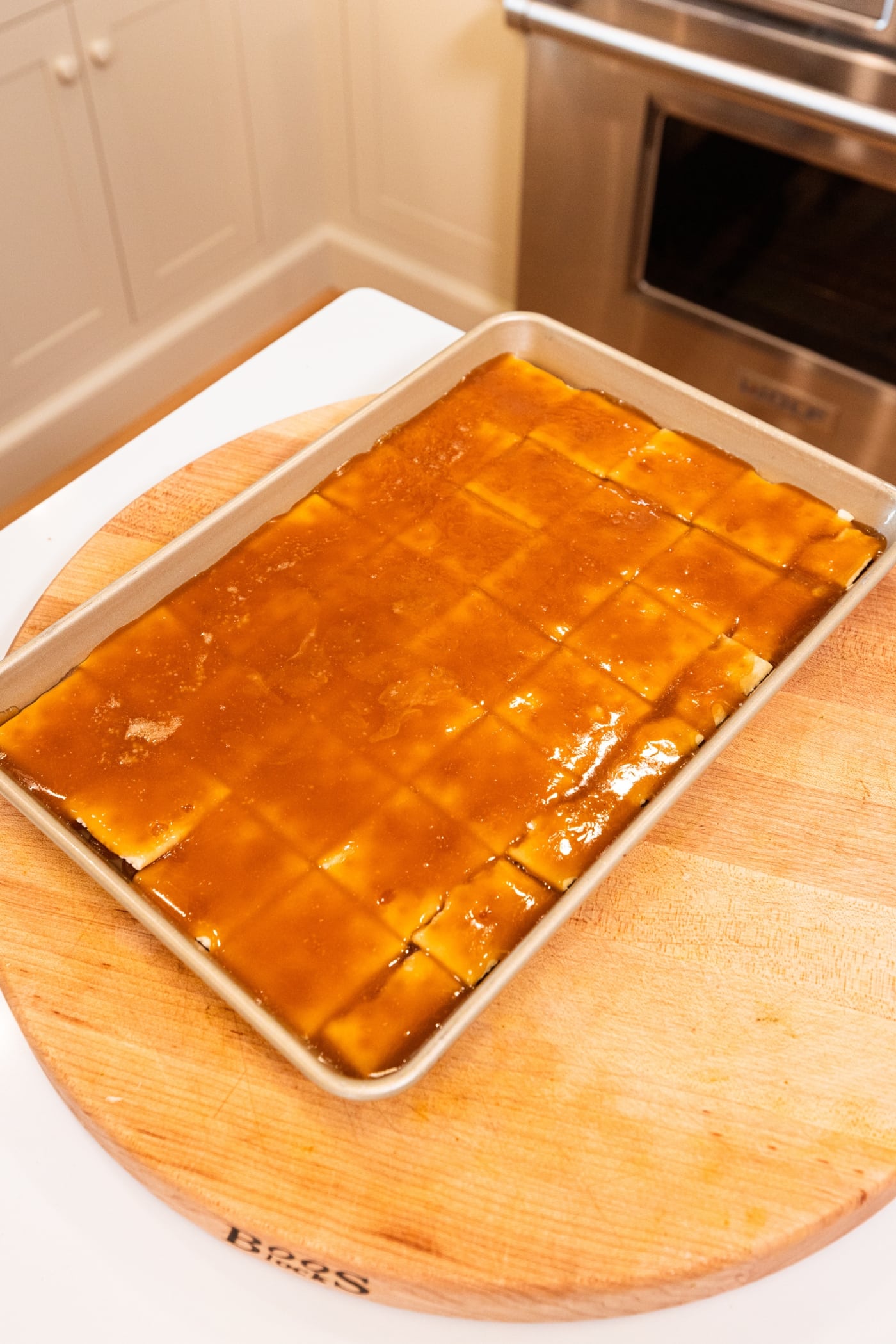 Gold baking pan with saltine crackers spread out in an even layer with caramel poured over the top.