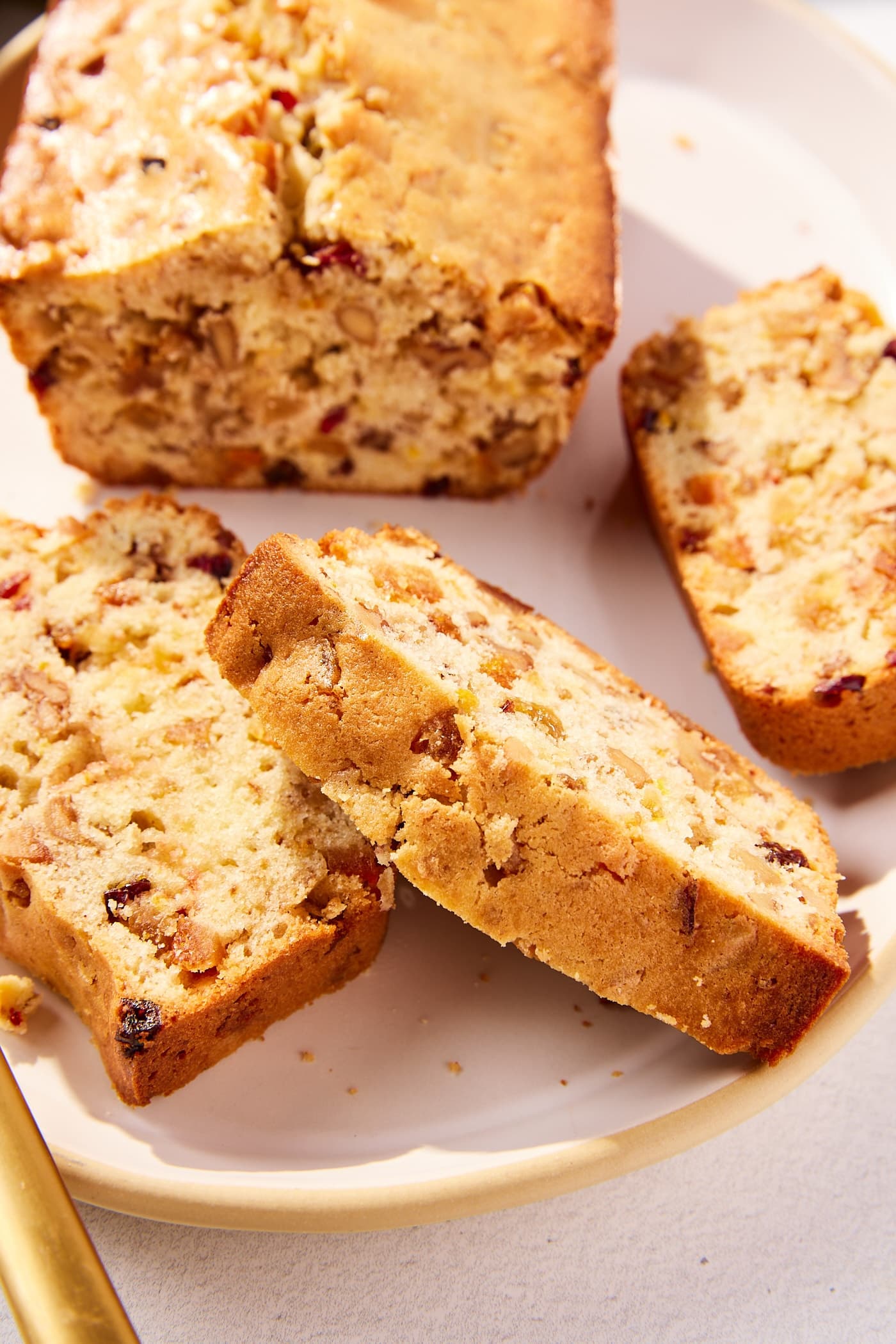 Slices of white fruitcake resting against each other with rest of loaf in background.