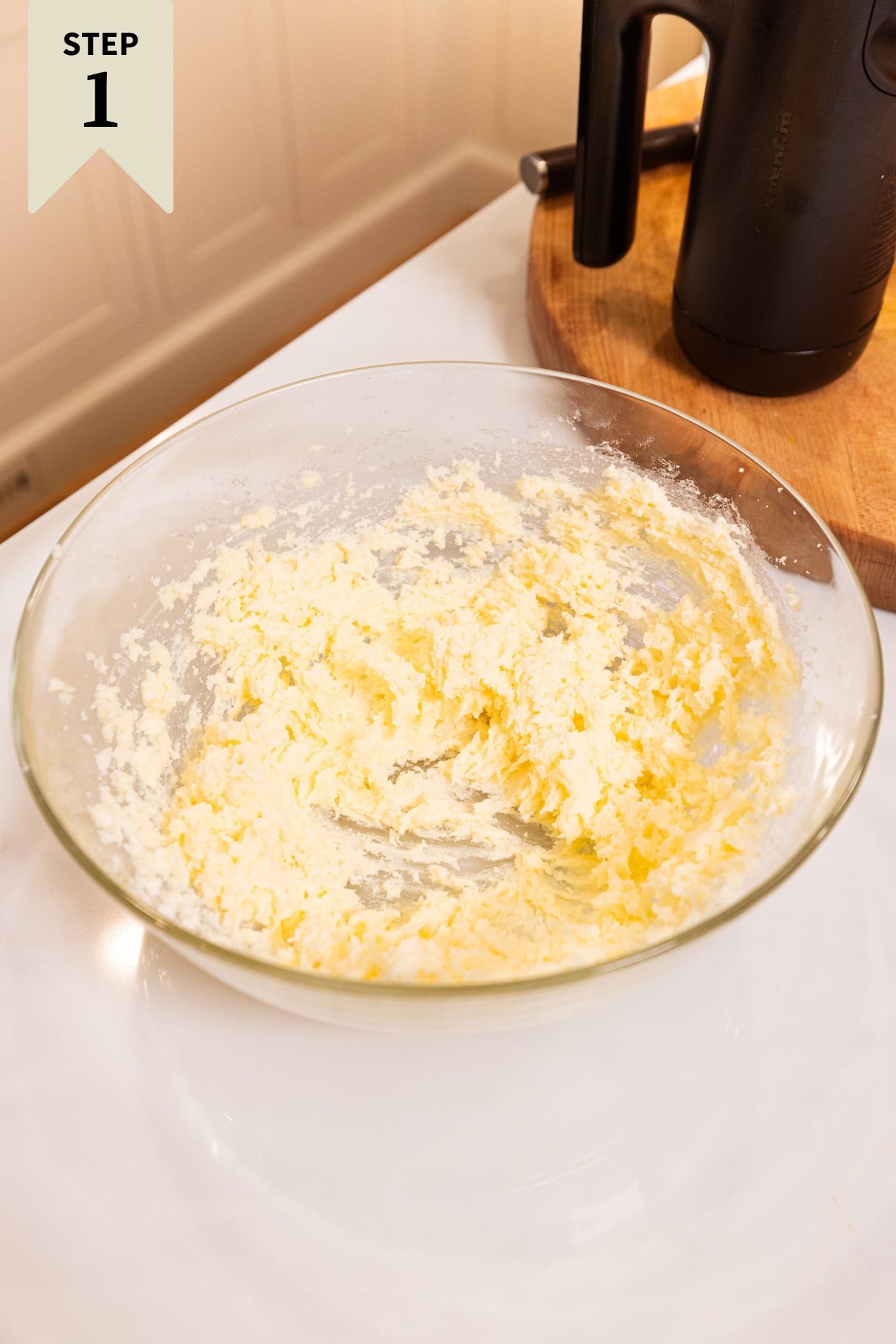 Glass bowl filled with butter and sugar after being creamed together with a hand mixer.