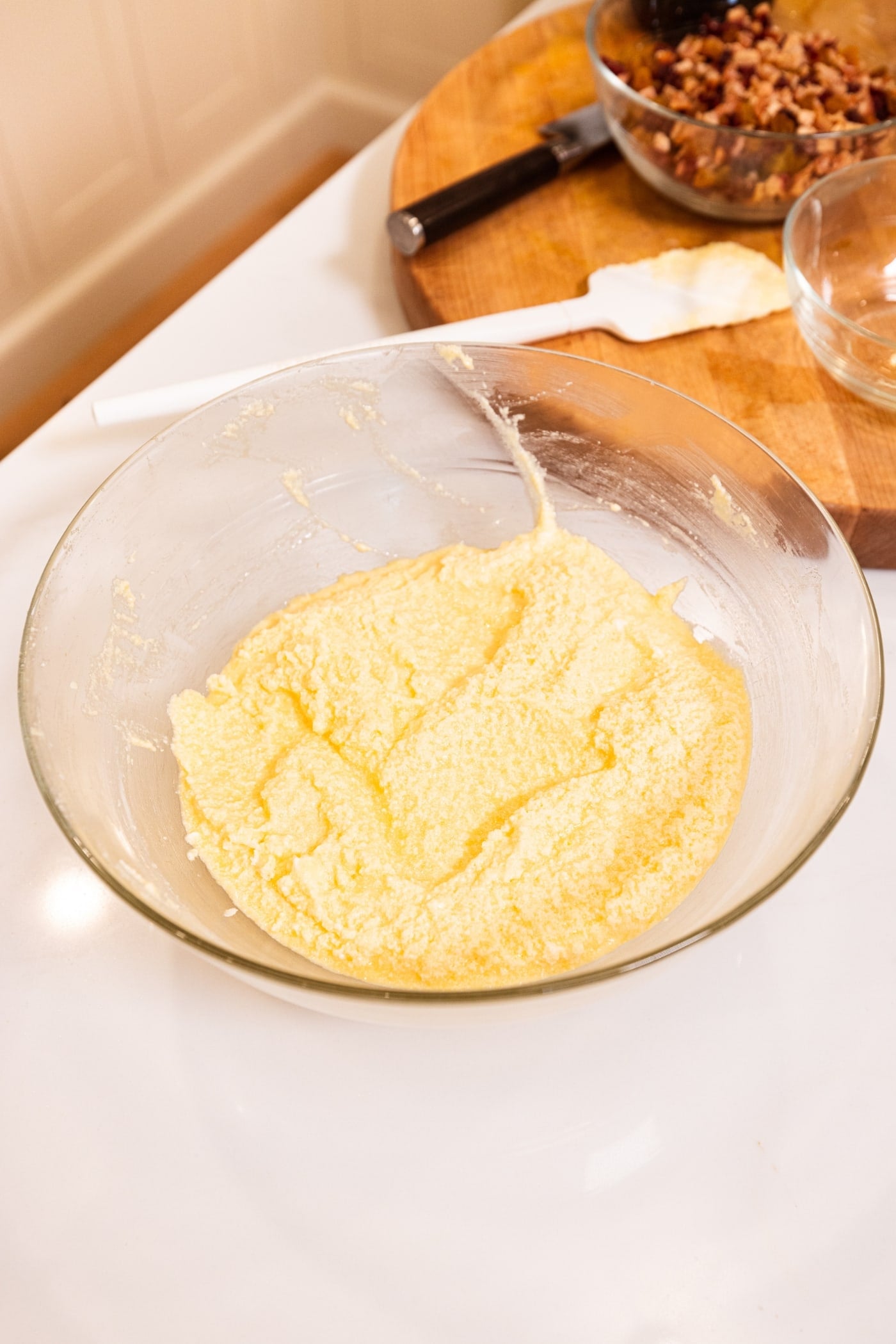 Glass bowl filled with creamed butter and sugar with plastic spatula in the background.