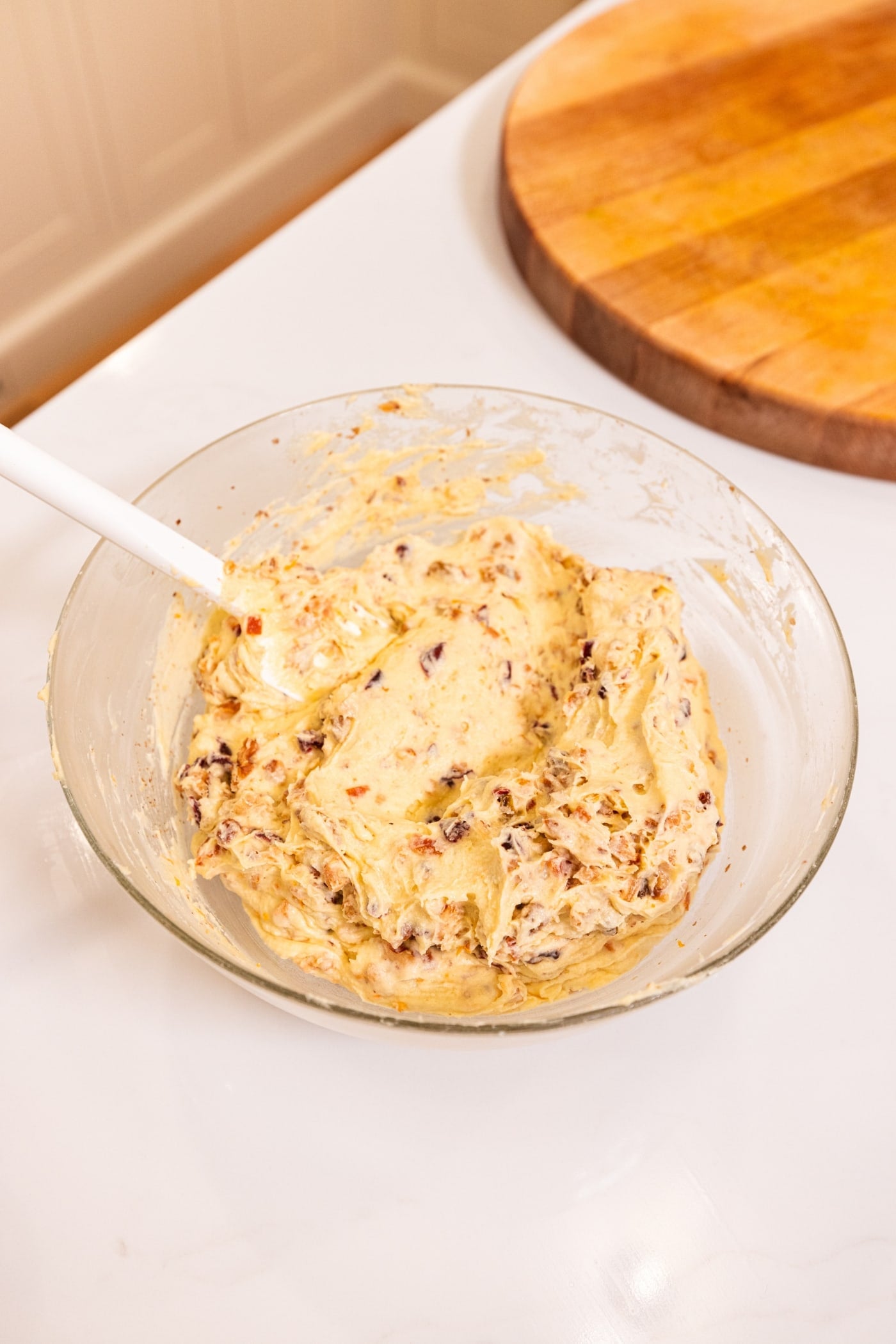 Glass bowl with batter after mixing in yuletide mix with spatula still in bowl.