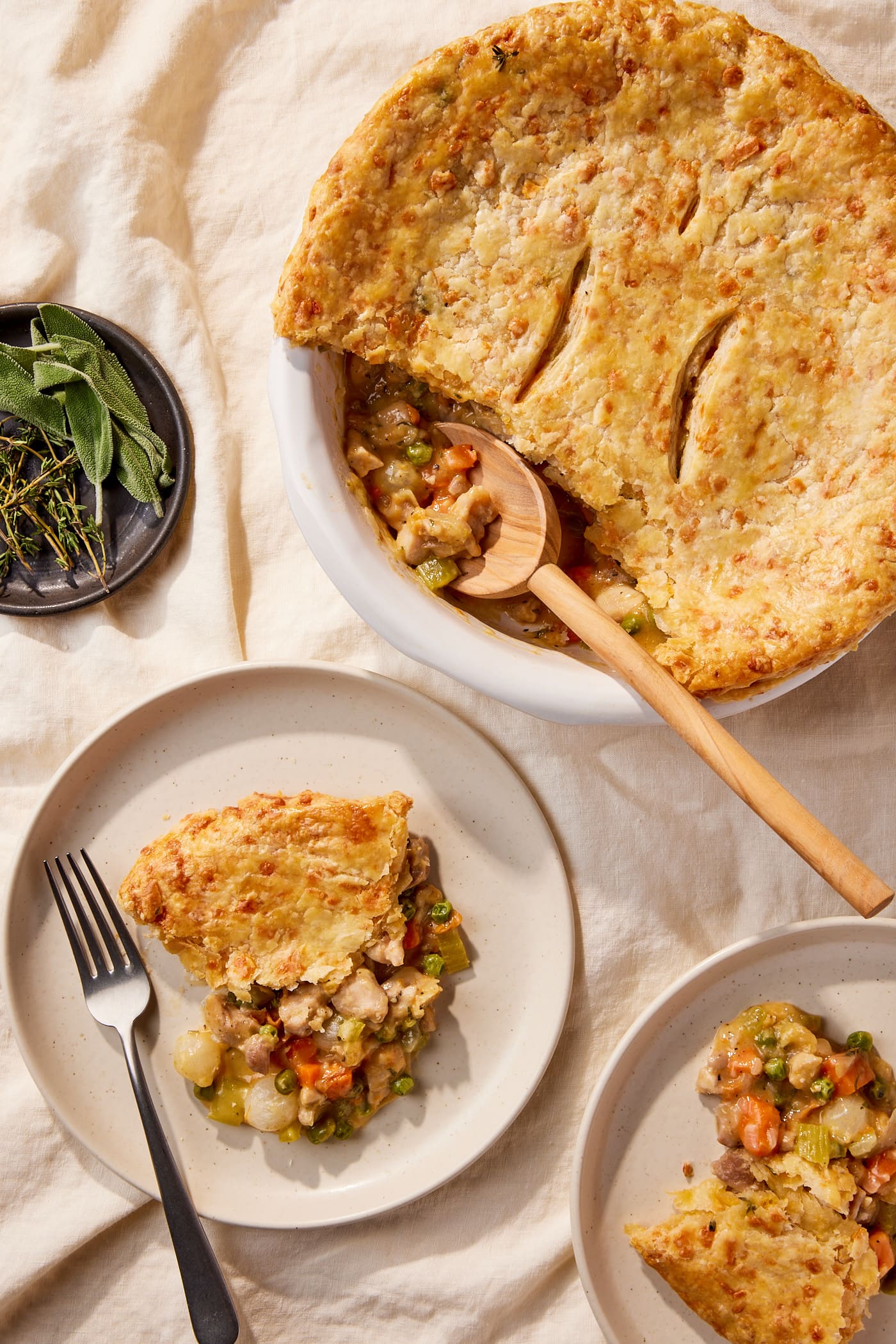 Two plates filled with servings of chicken pot pie with rest of main dish with spoon resting.