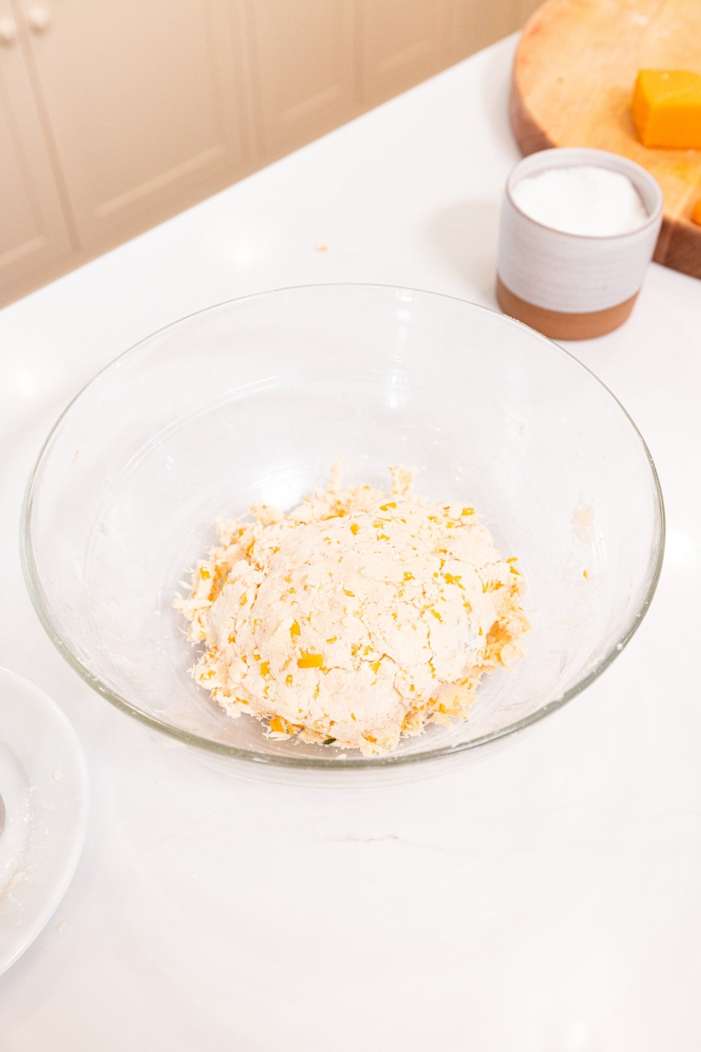 Pressed together dough mixture in glass bowl on white surface in kitchen.