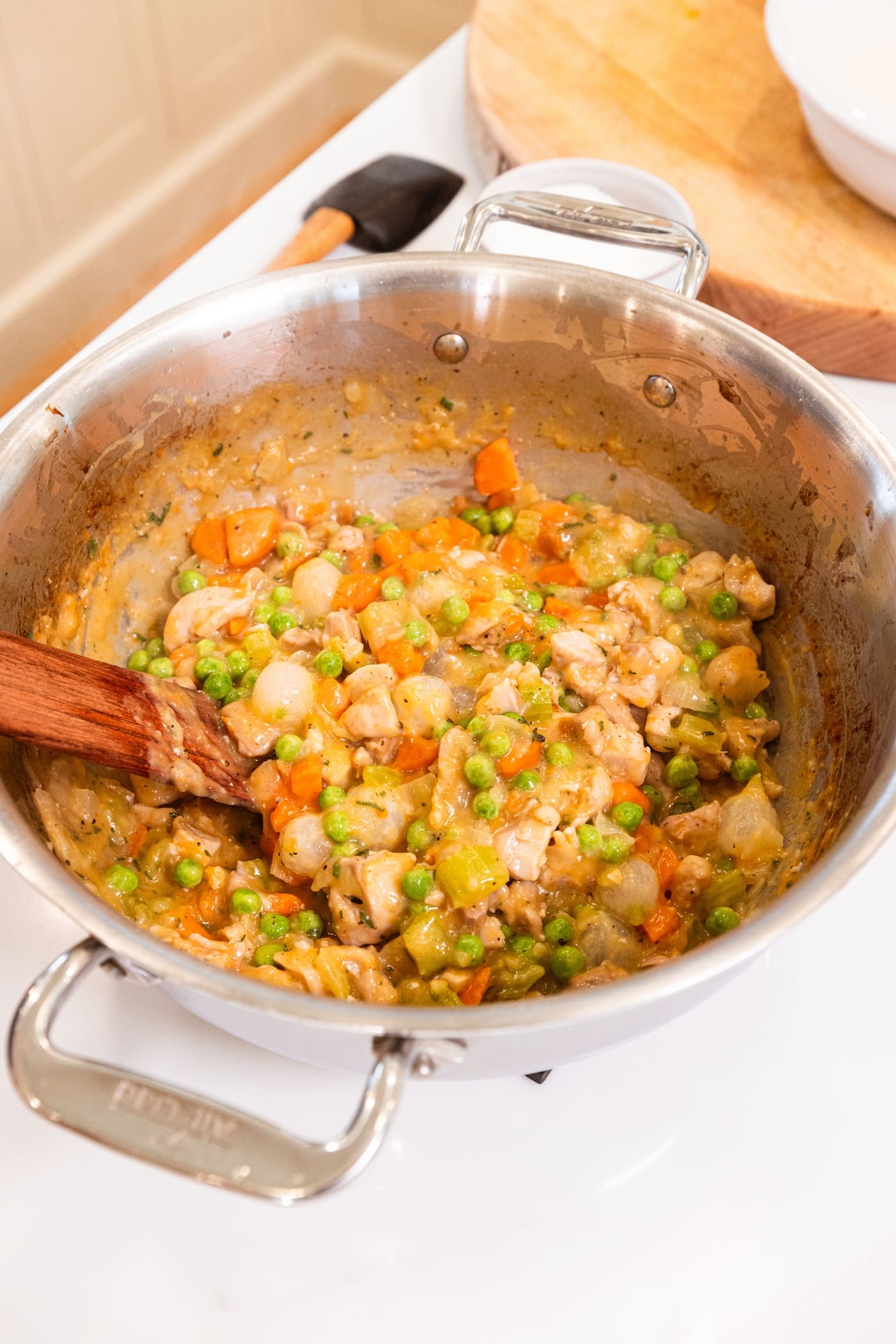 Cooked and thickened mixture of filling for chicken pot pie sitting in large metal stockpot.