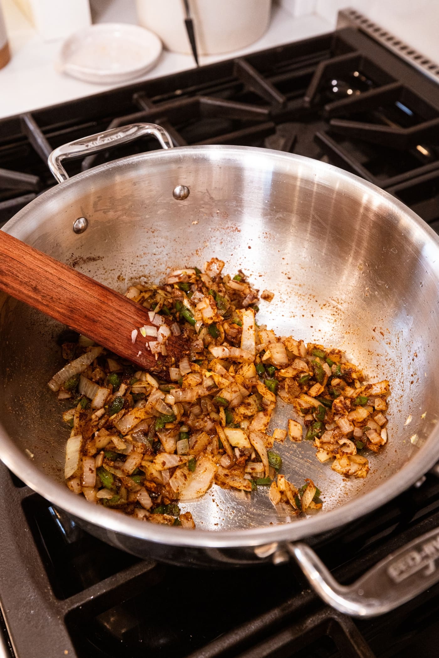 Cooked mixture of diced onion and jalapeño with spices in large stockpot on the stovetop.