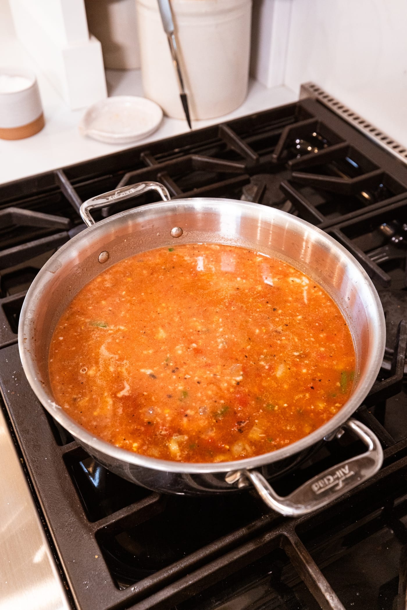 Soup mixture on the stovetop with pureed white beans added on top of chicken stock and crushed tomatoes.