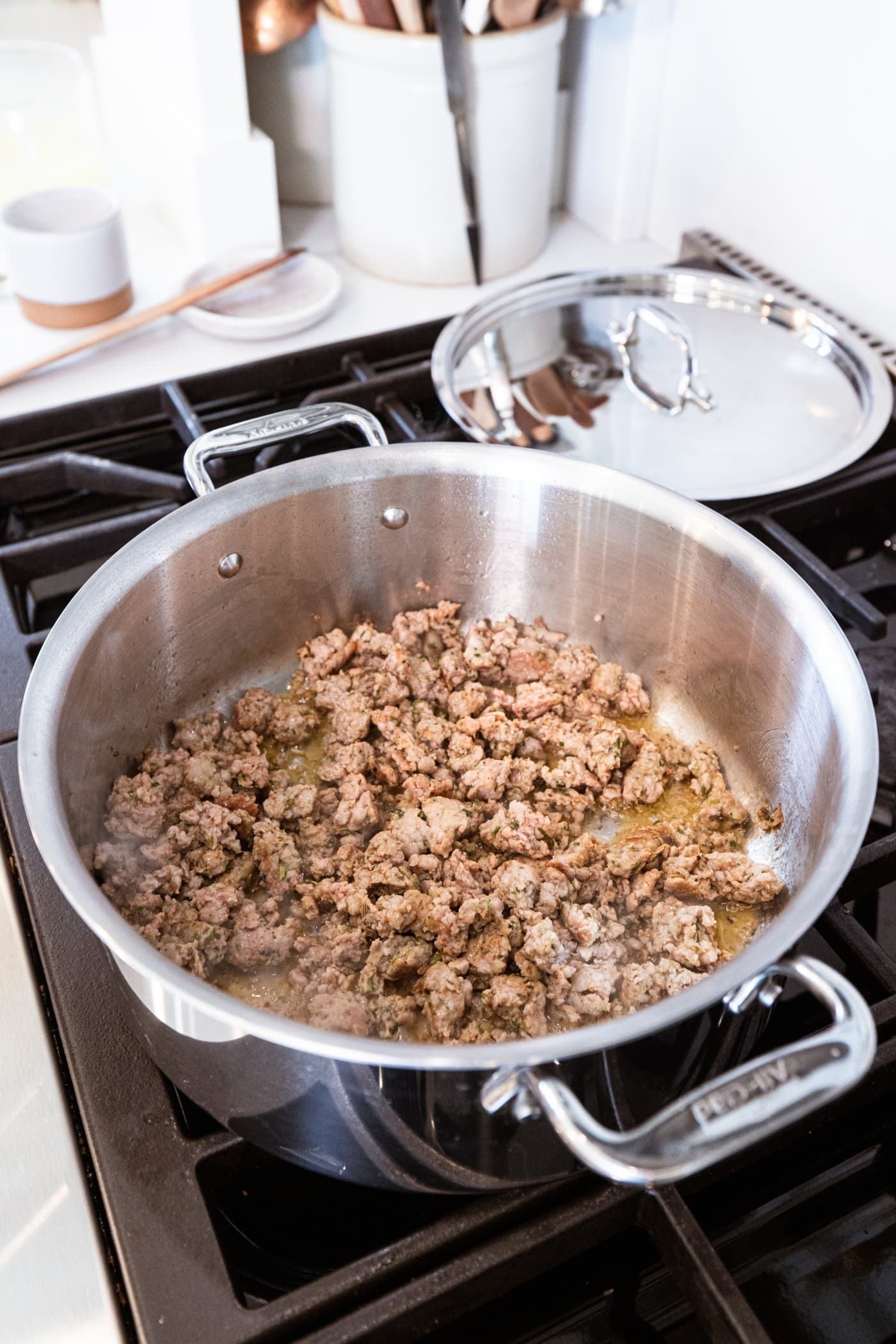 Cooked Italian sausage in the bottom of a metal stockpot on the stovetop.