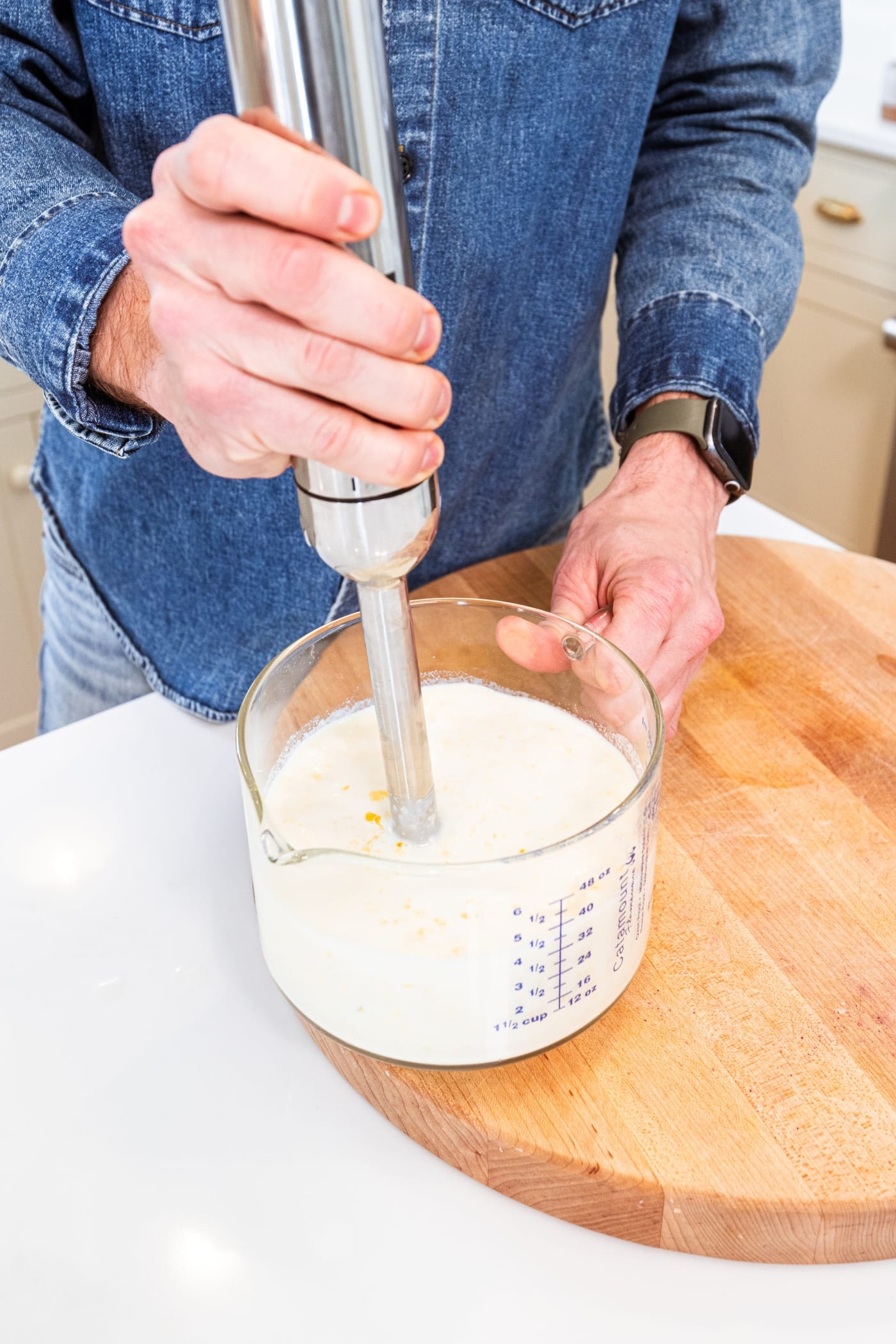 Hand using immersion blender to blend together sweet corn and milk to create a puréed mixture.