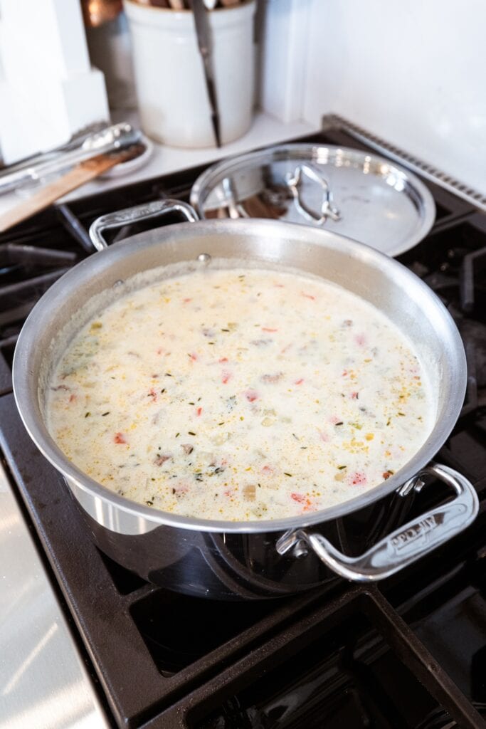 Creamy corn chowder sitting in a large metal stockpot on the stovetop with white creamy color.