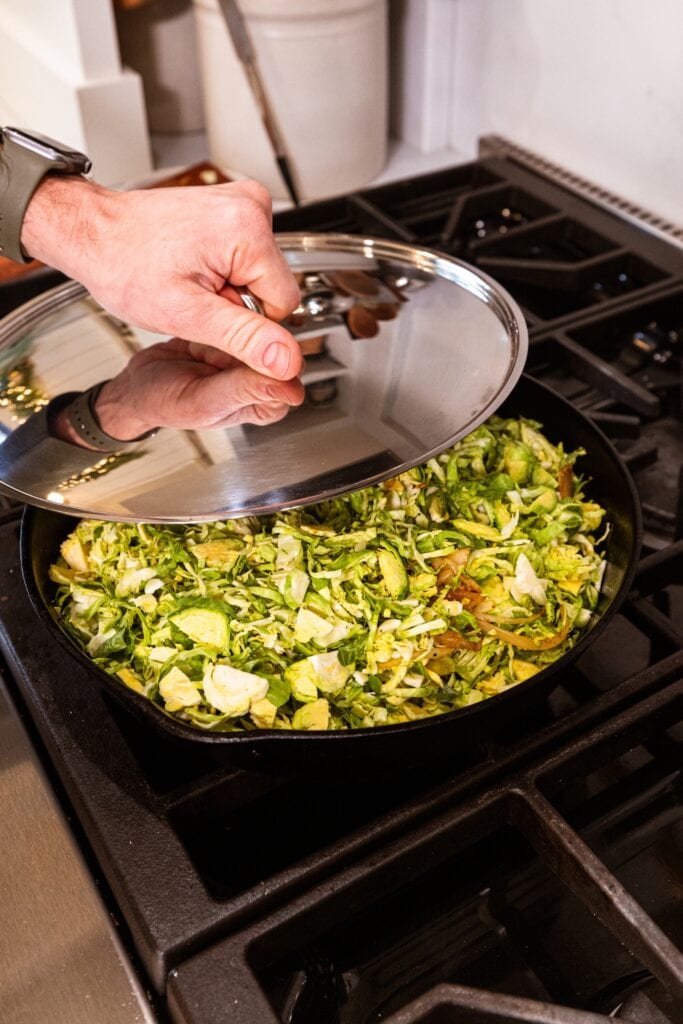Hand about the place the lid over a cast iron skillet filled with uncooked strips of Brussels sprouts.
