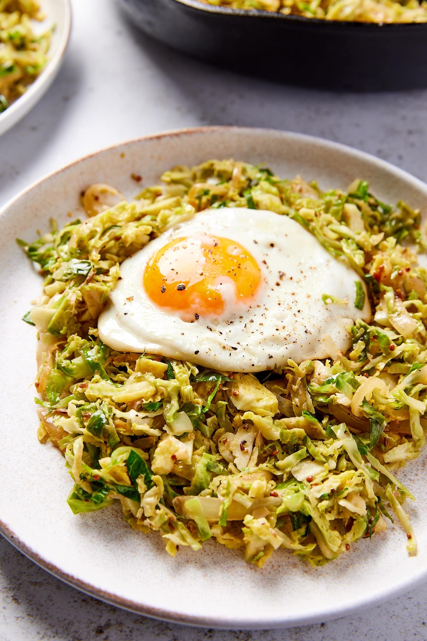 Large white plate filled with a serving of Brussels sprouts has with a fried egg on top.