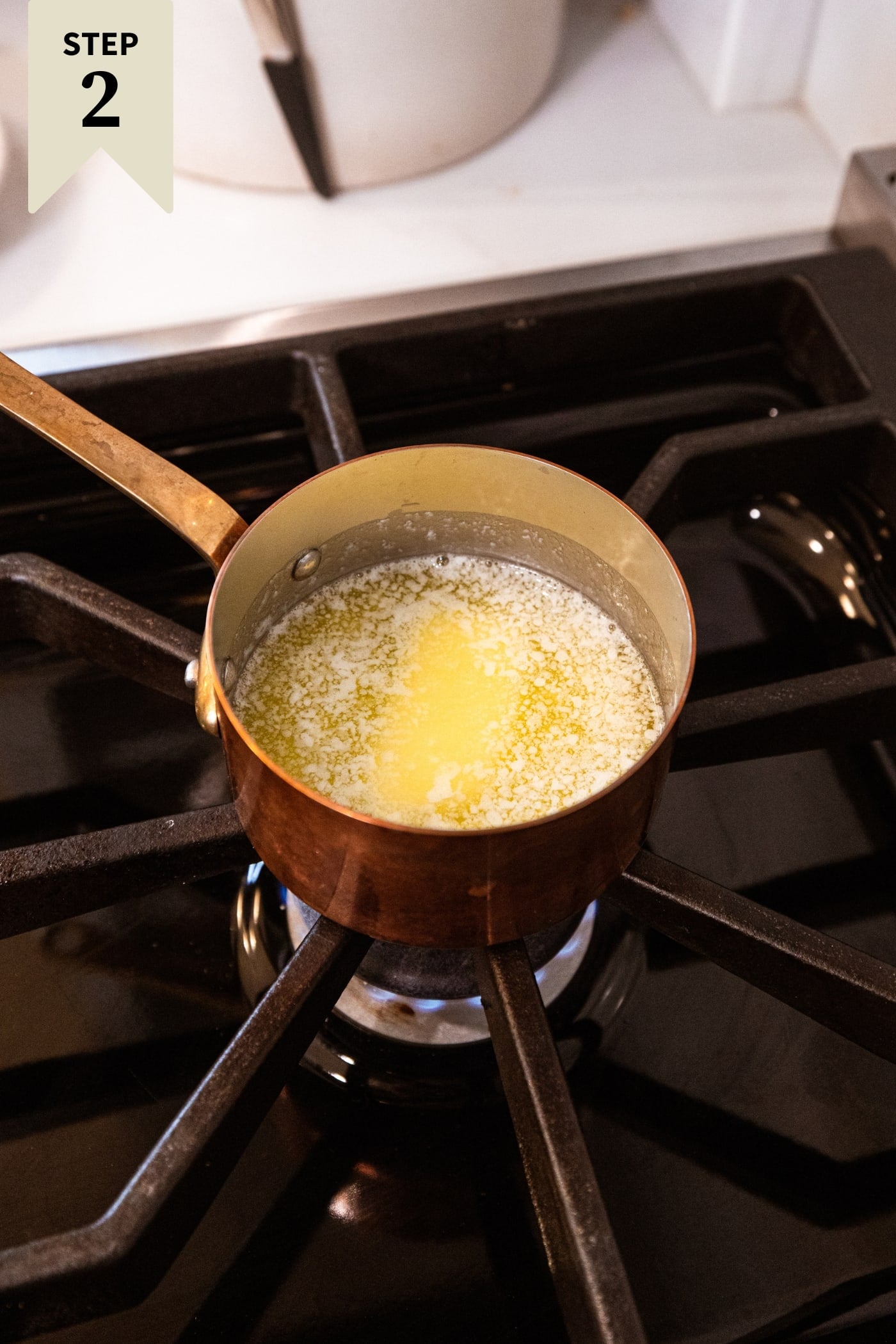 Copper pot on the stovetop with melting butter over low heat.