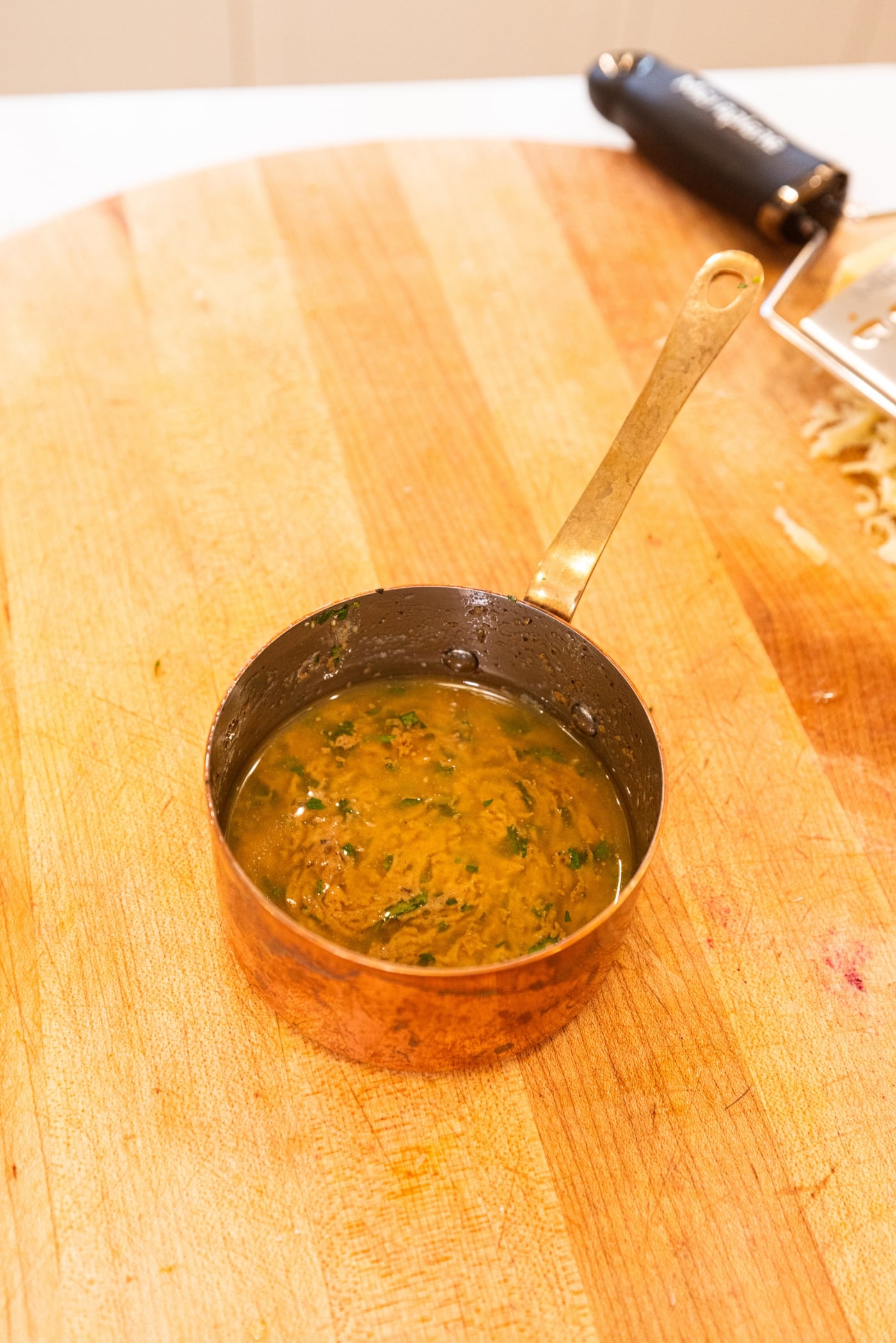 Copper pot filled with melted cowboy butter with herbs and mustard mixed together.