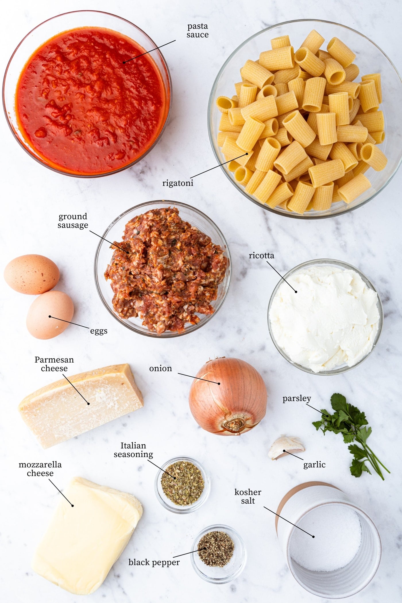 White marble surface filled with all ingredients for lasagna casserole including tomato sauce, pasta, spices, meat, and more.