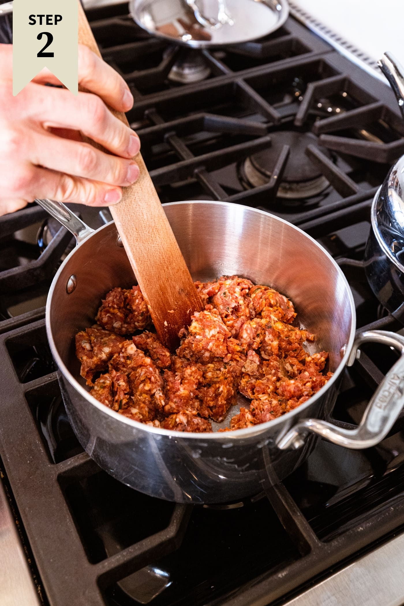 Metal saucepan filled with raw sausage before being cooked on the stovetop.
