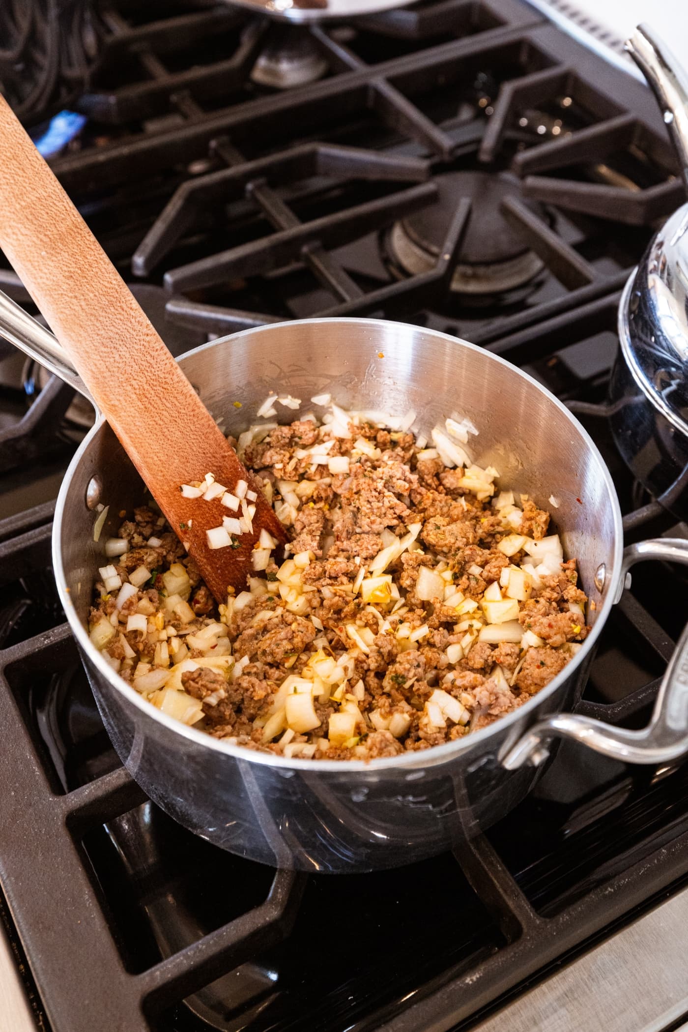 Cooked meat mixture with raw onions before being cooked fully on the stovetop.