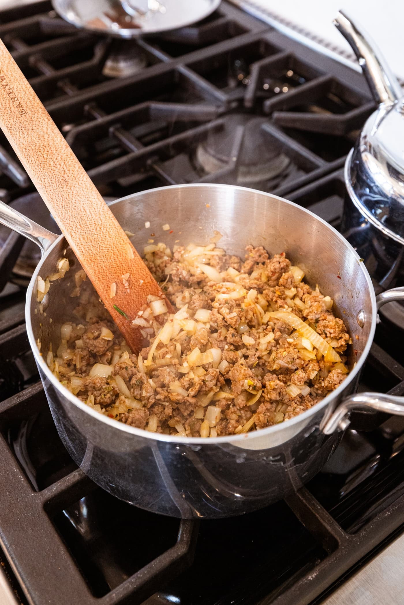 Small metal saucepan filled with cooked meat mixture and onions.