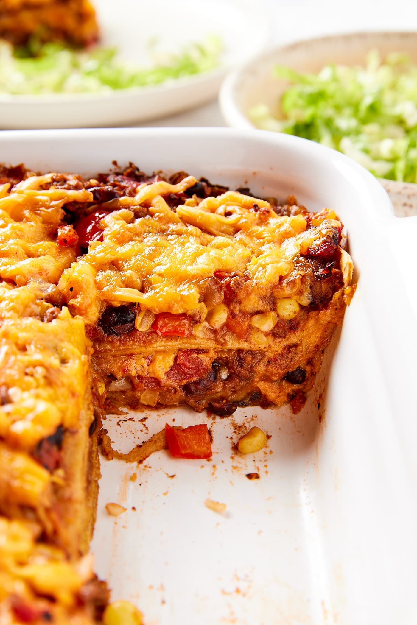 White casserole dish filled with slices of loaded taco squares casserole with pieces removed showing interior texture of the casserole.