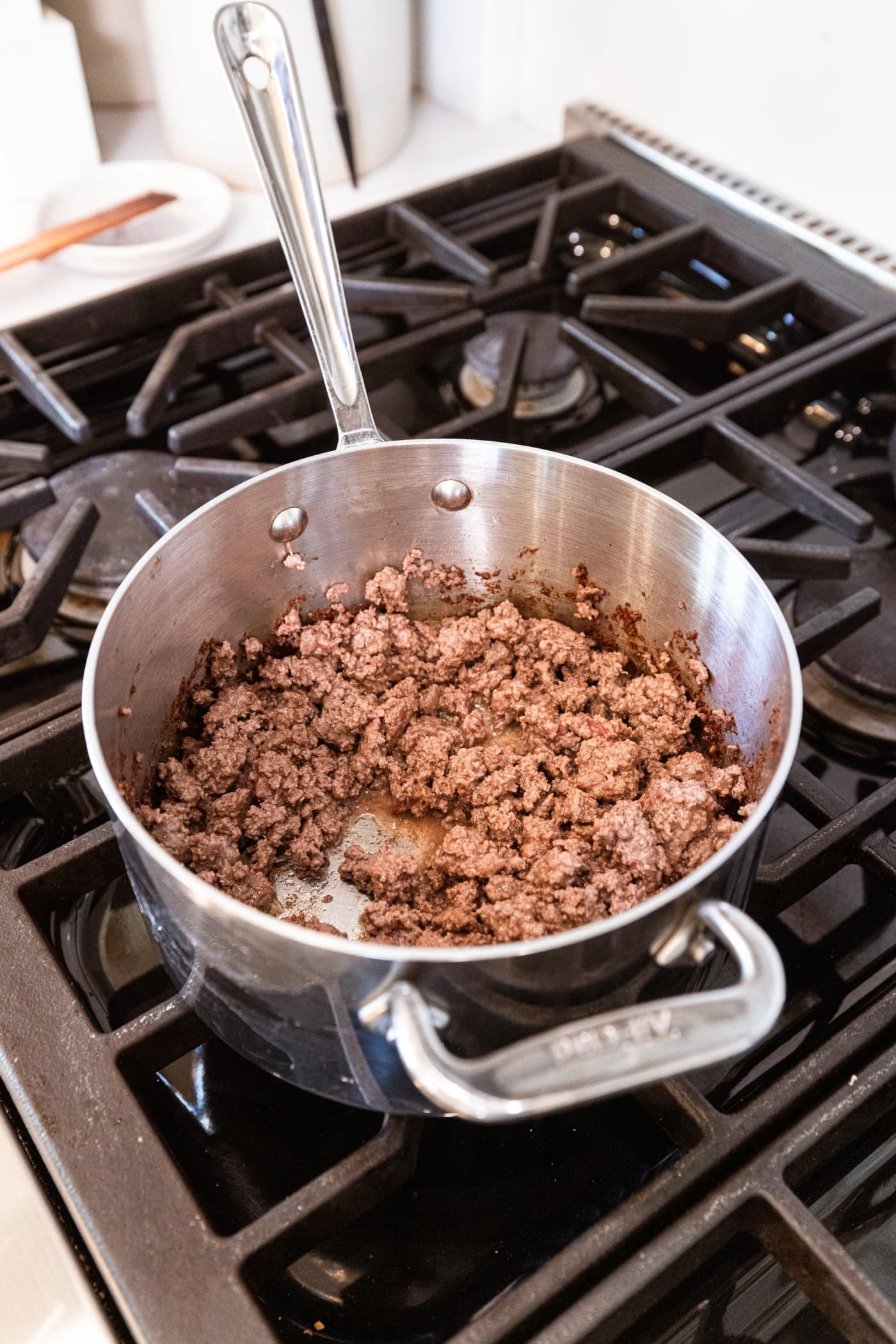 Cooked ground beef in metal saucepan on the stovetop after being browned.