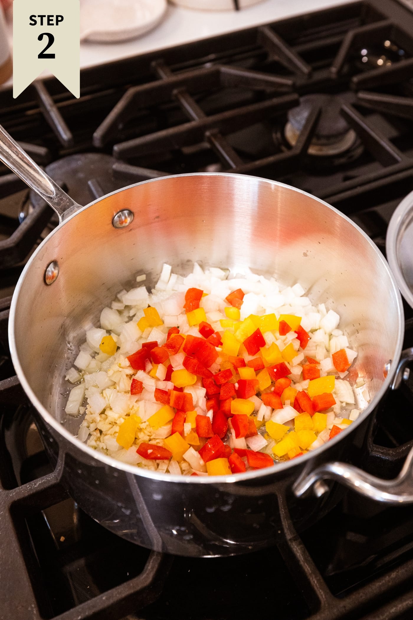 Metal pan filled with diced onion and bell peppers sautèing on the stovetop.